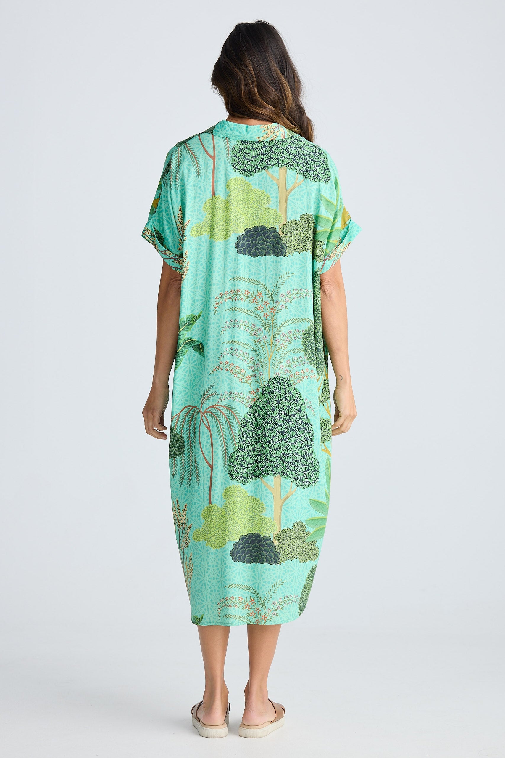 Woman wearing a green patterned dress on a white background