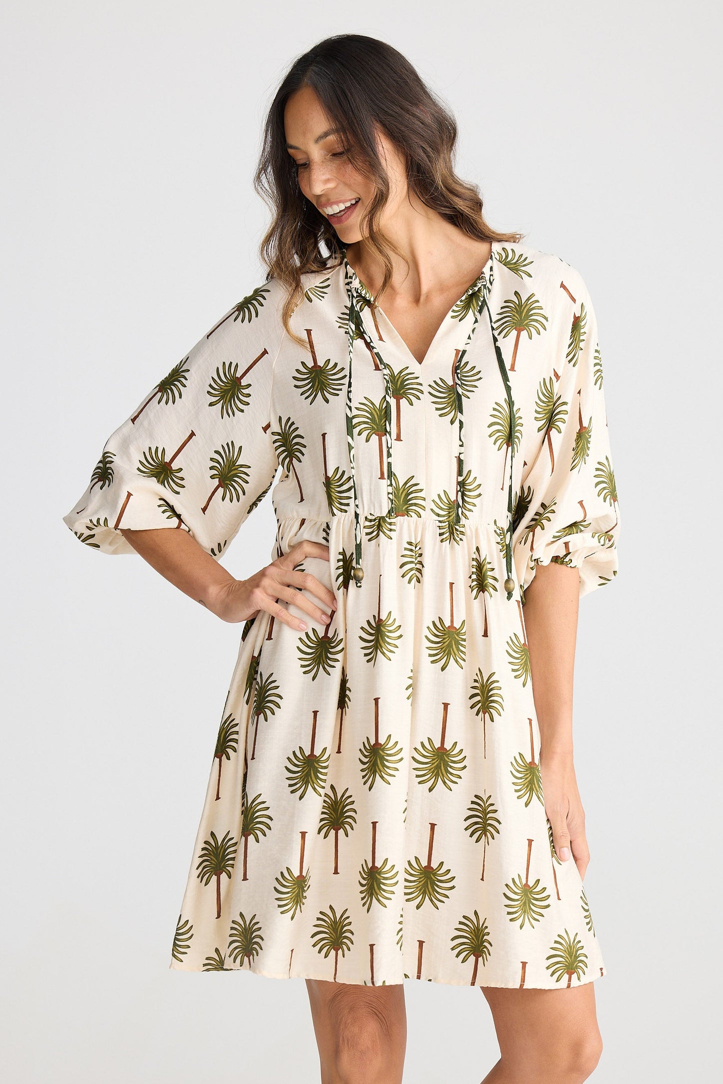 Woman wearing a palm tree patterned dress on a white background