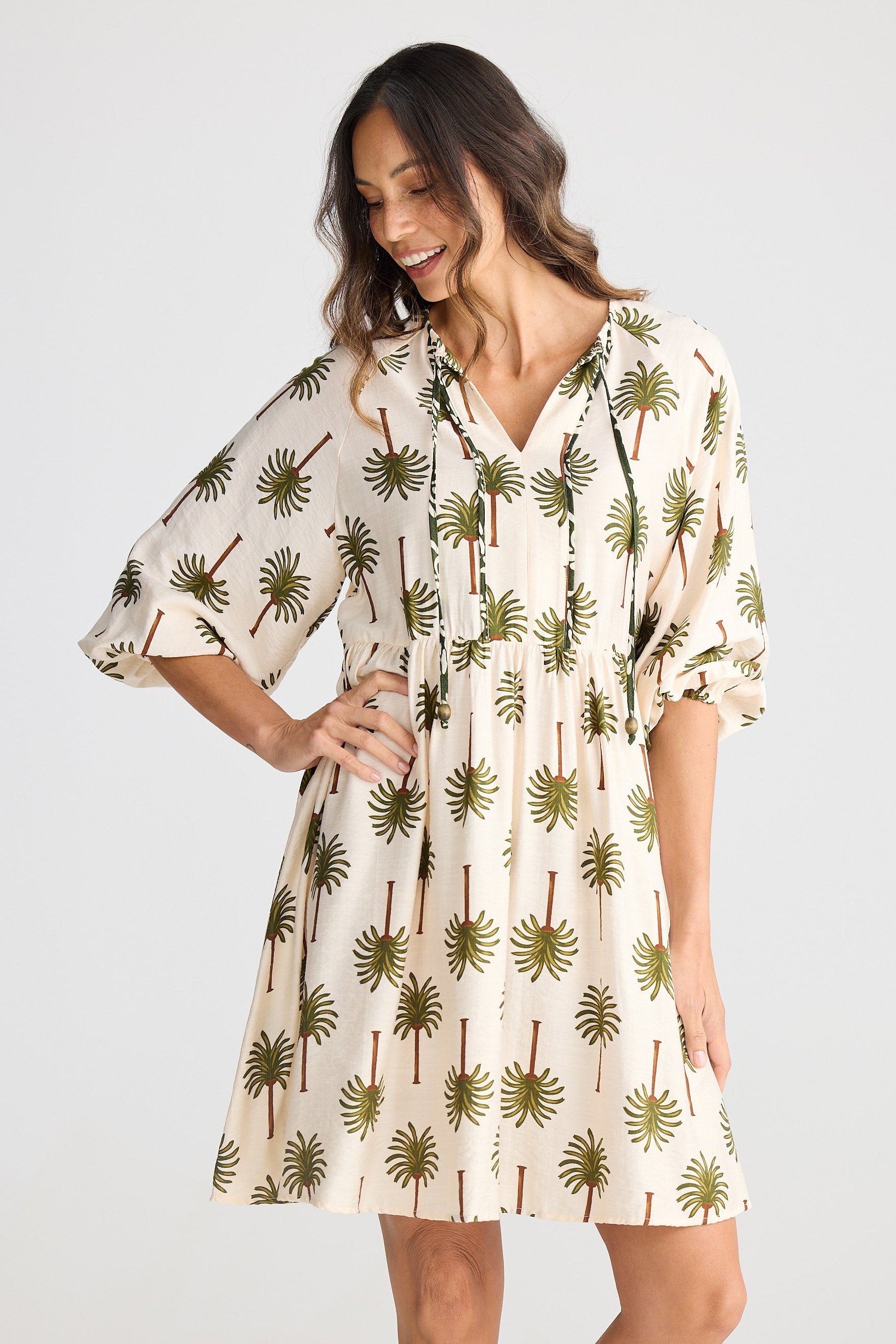 Woman wearing a palm tree patterned dress on a white background
