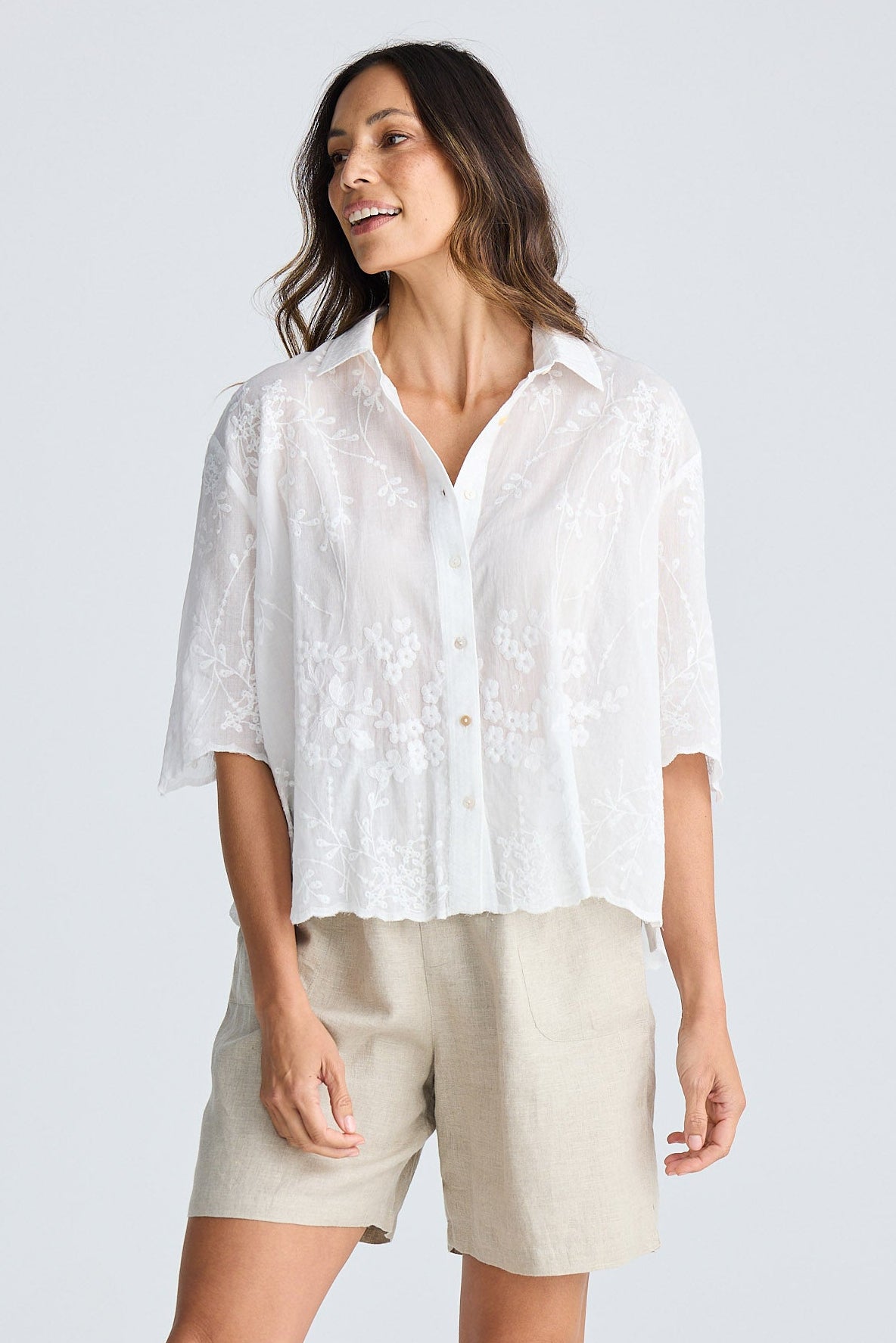Woman wearing a white shirt and beige shorts on a white background