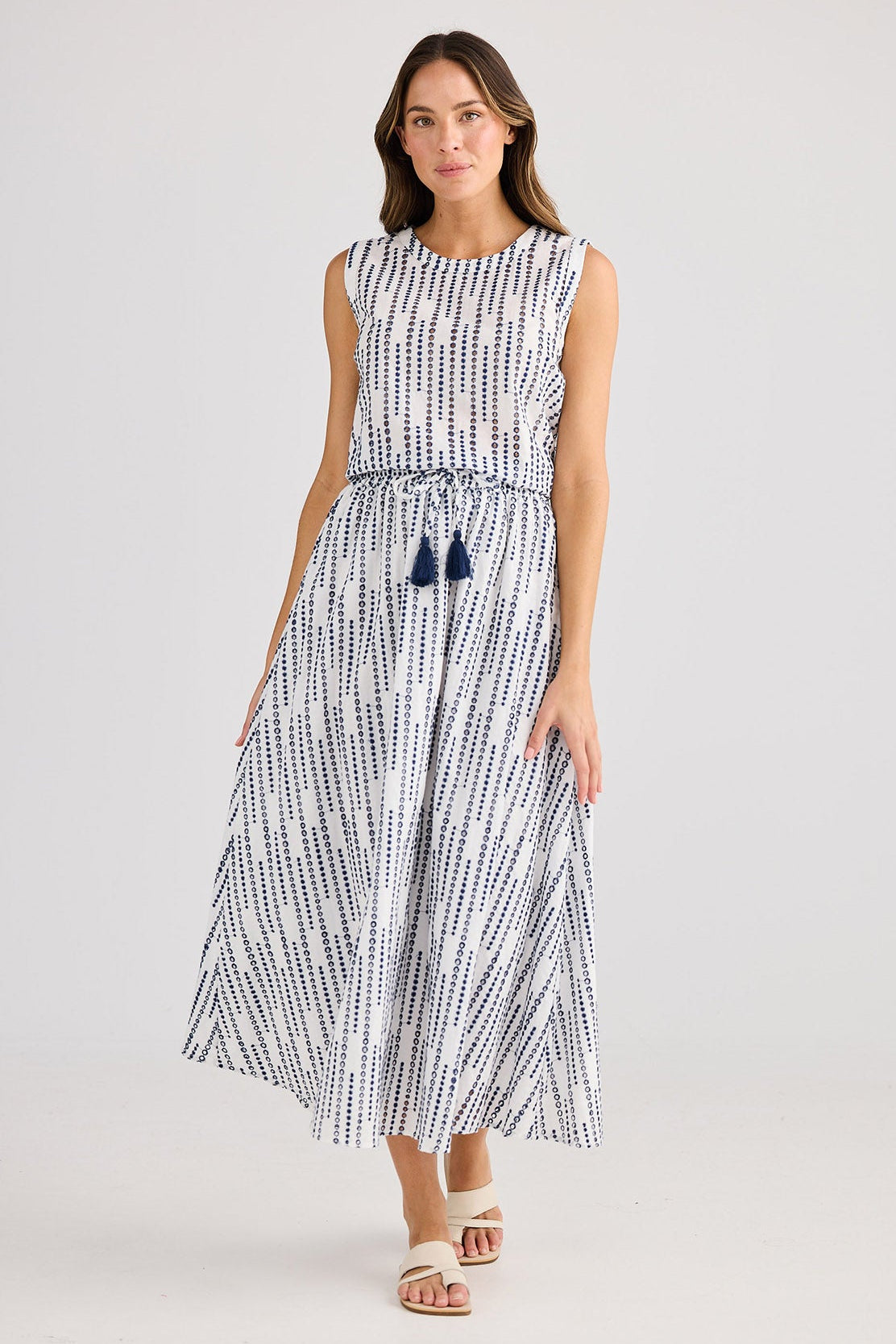 Woman wearing a sleeveless top and matching skirt with a geometric pattern on a plain background