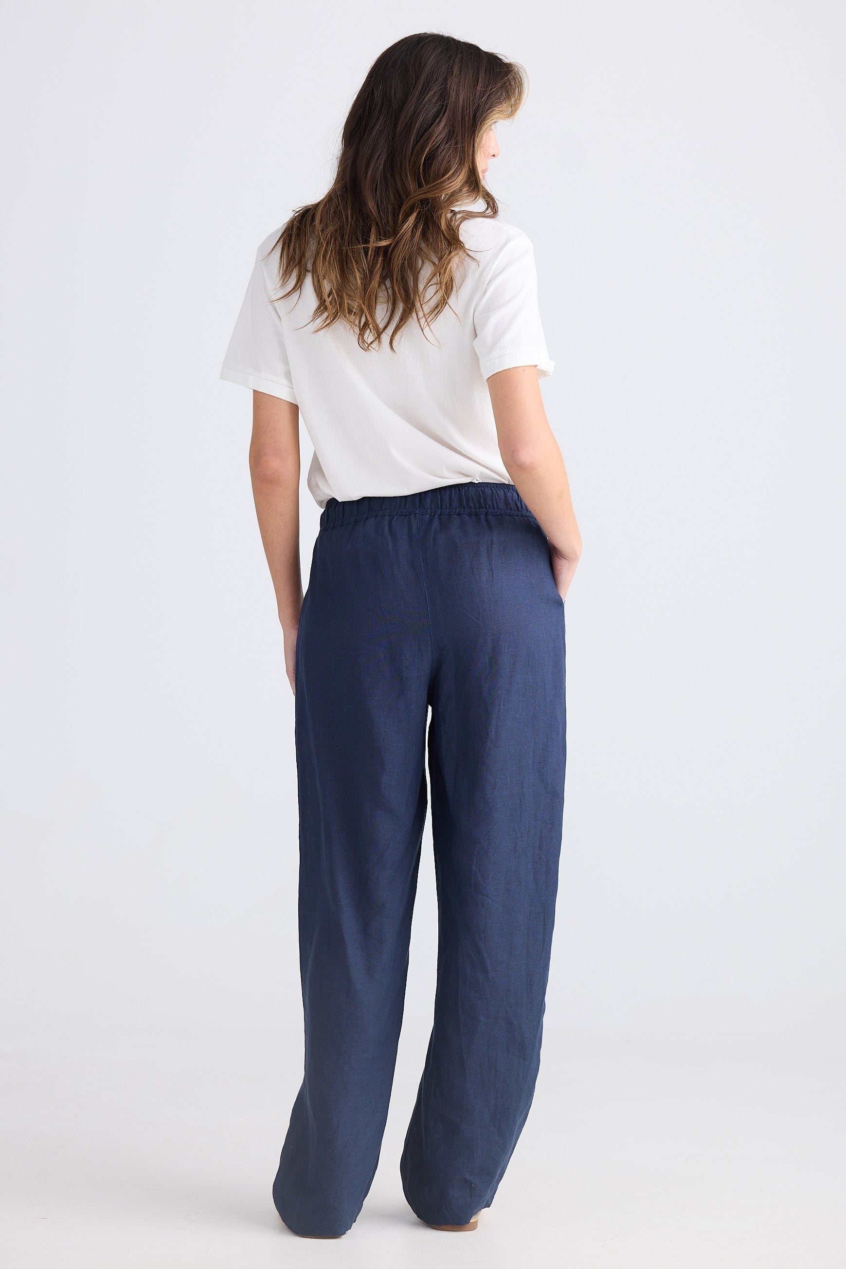 Woman wearing navy pants and a white shirt on a white background