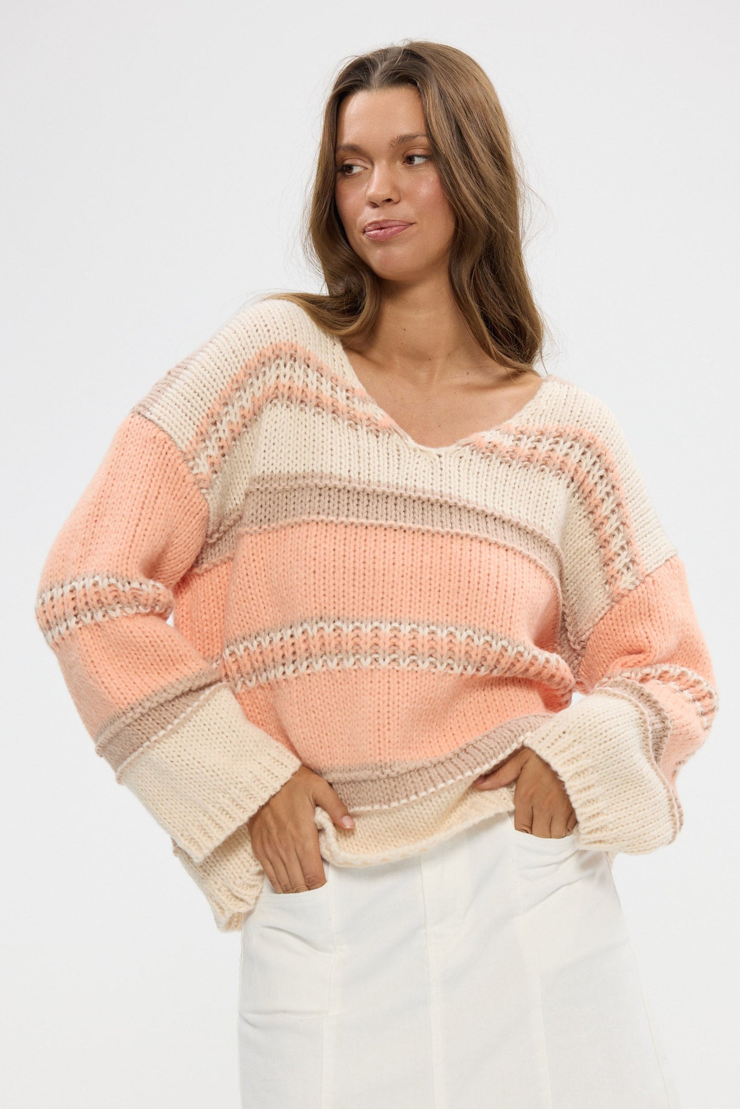 Woman wearing a pastel striped sweater against a white background