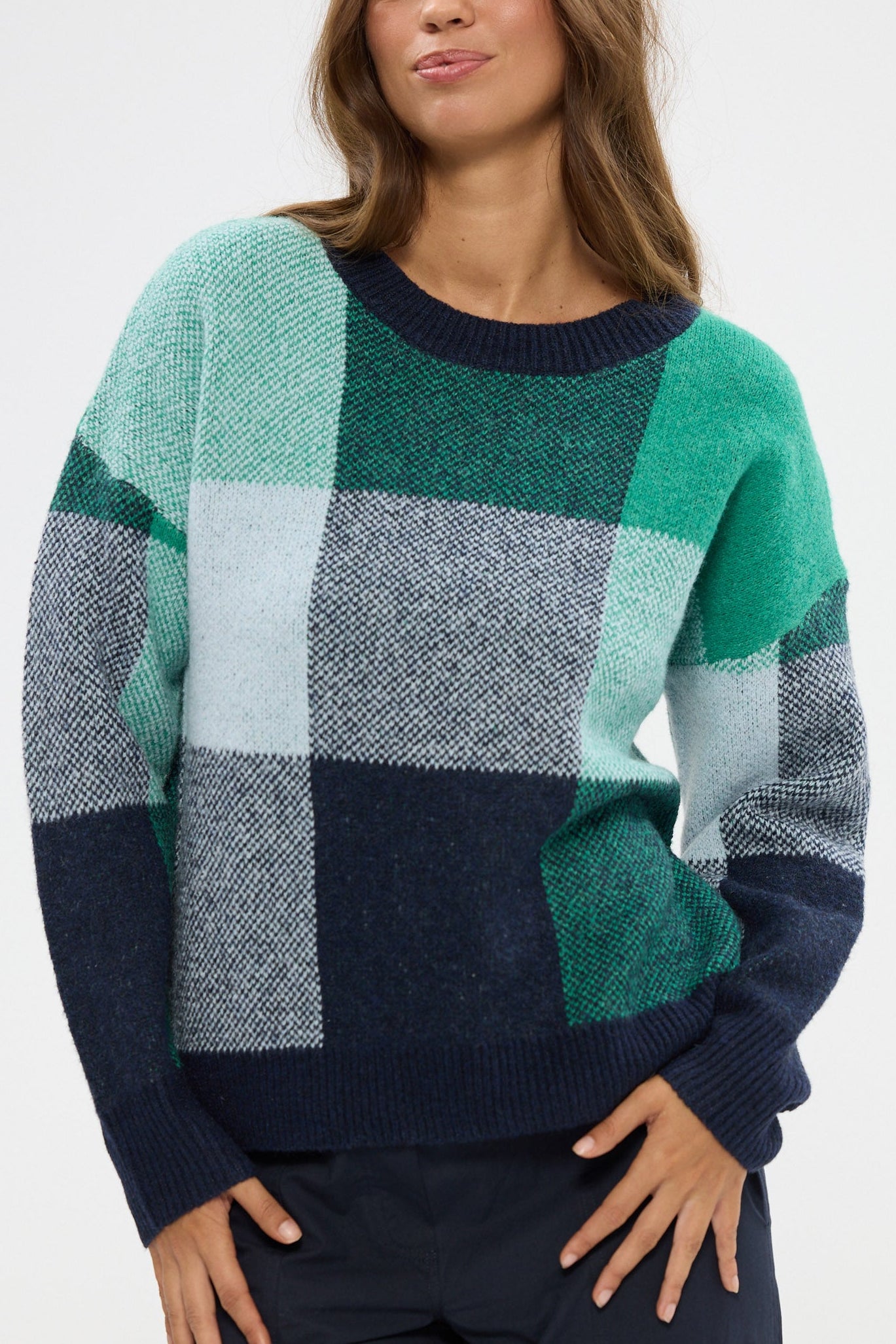 Woman wearing a checkered sweater with green, blue, and gray colors on a white background