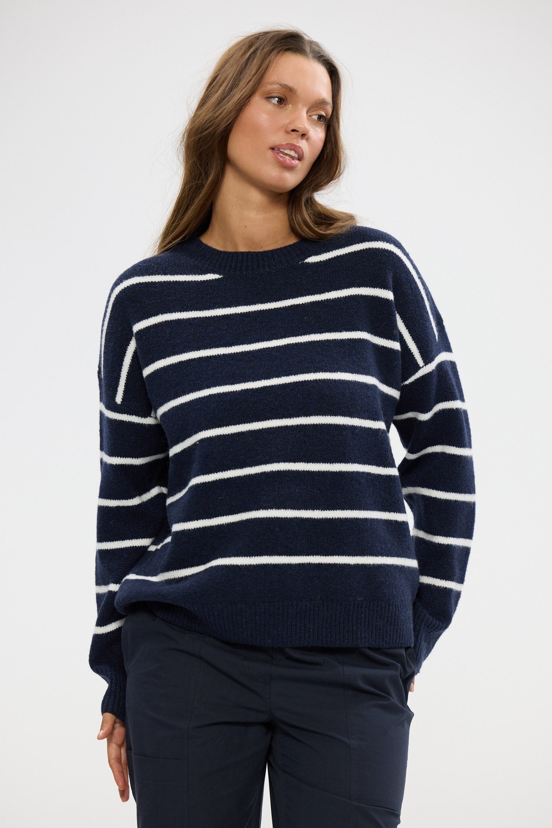 Woman wearing a navy and white striped sweater against a white background