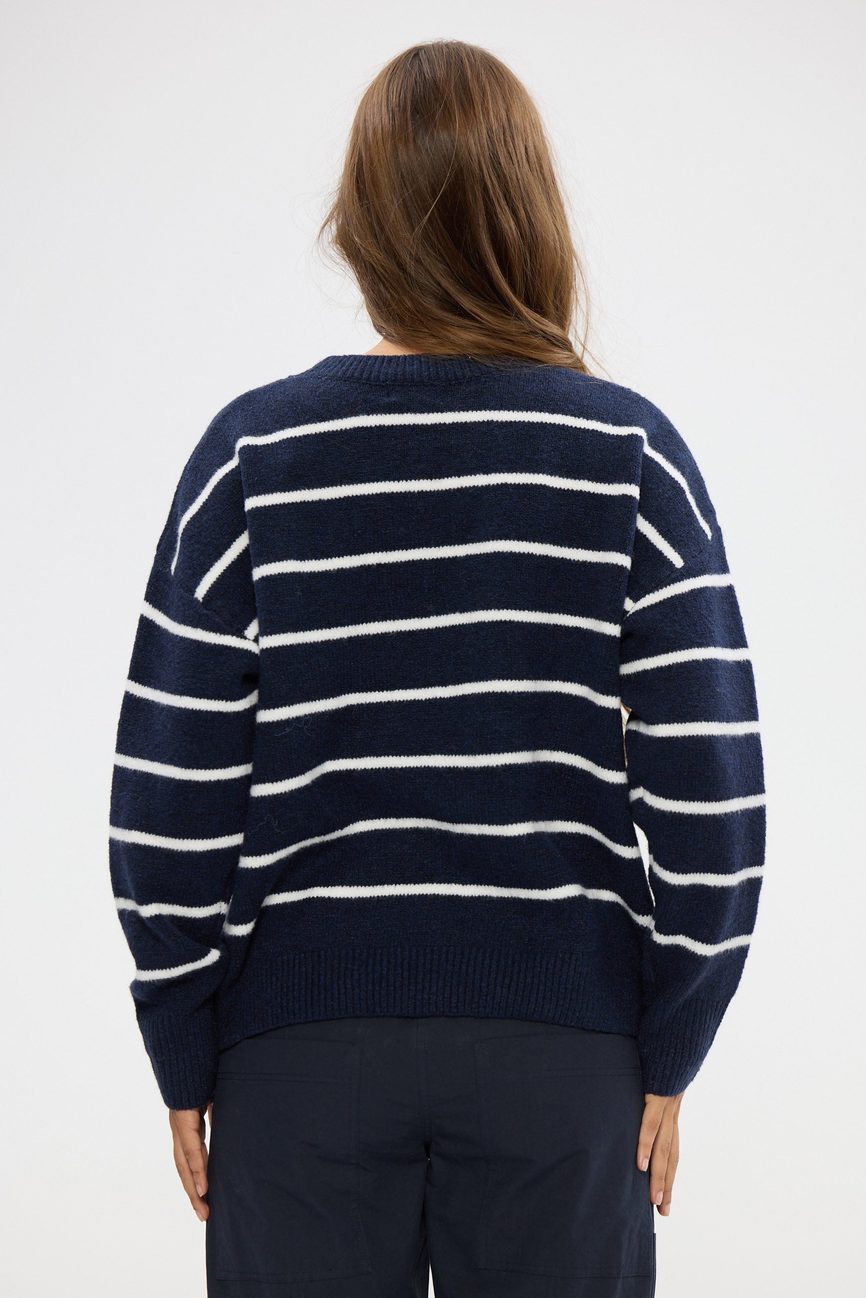 Person wearing a navy and white striped sweater on a white background