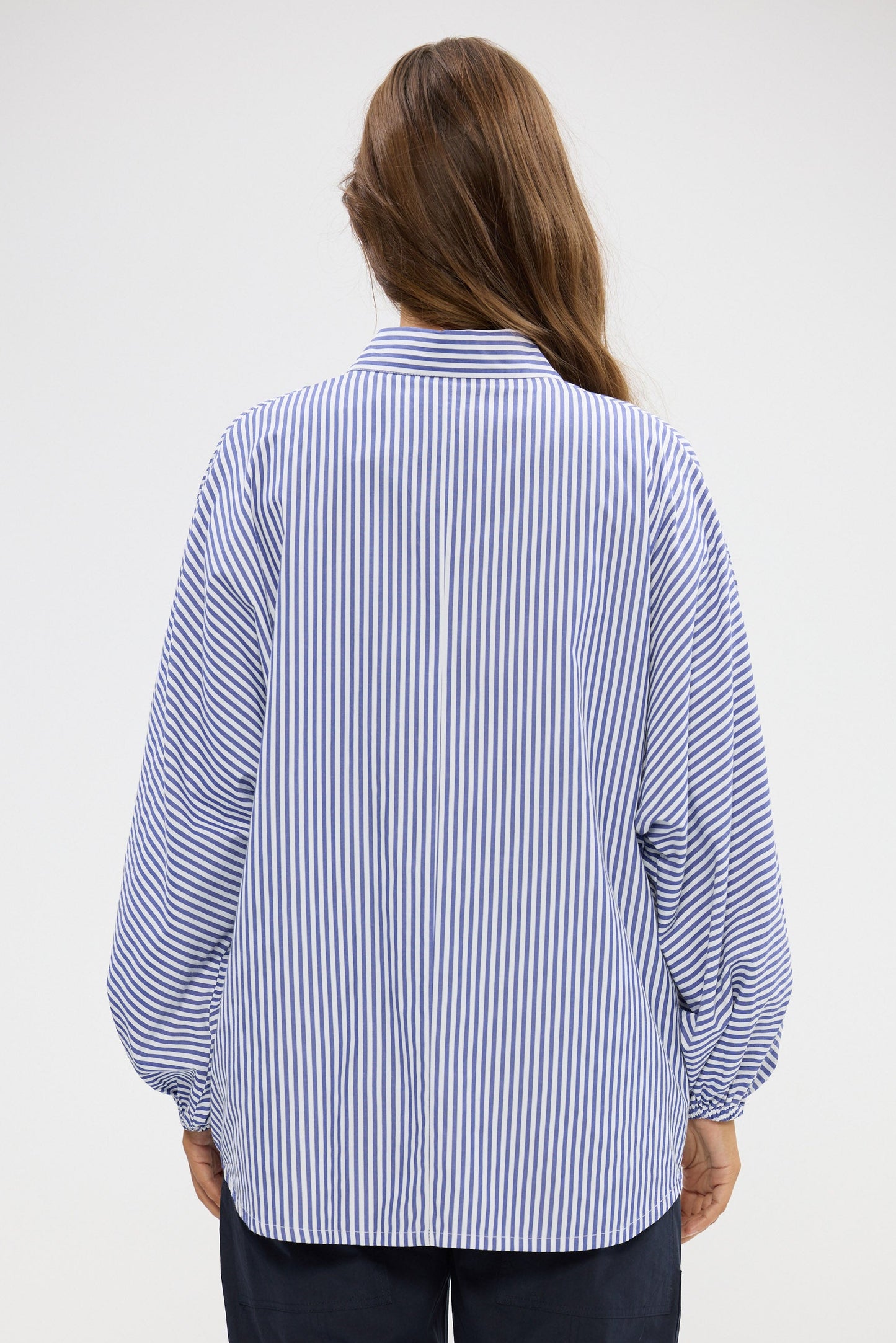 Person wearing a blue and white striped shirt on a plain background