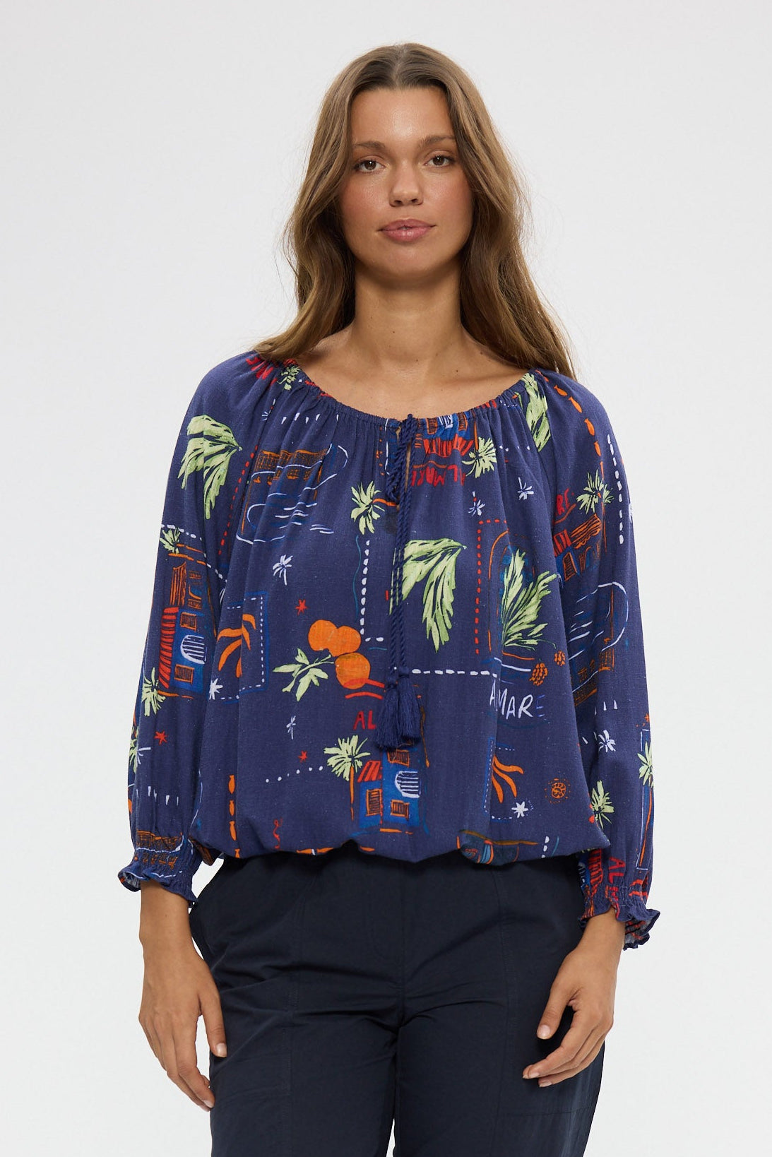 Woman wearing a blue floral blouse and dark pants on a white background