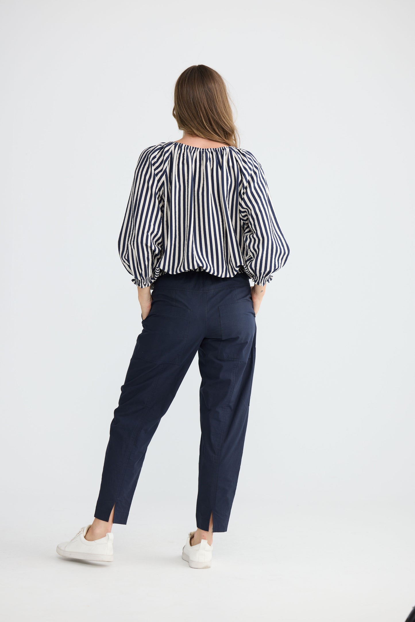 Model wearing Seaside Top Navy and White Stripe with neck ties and shirred cuffs, back view on white background