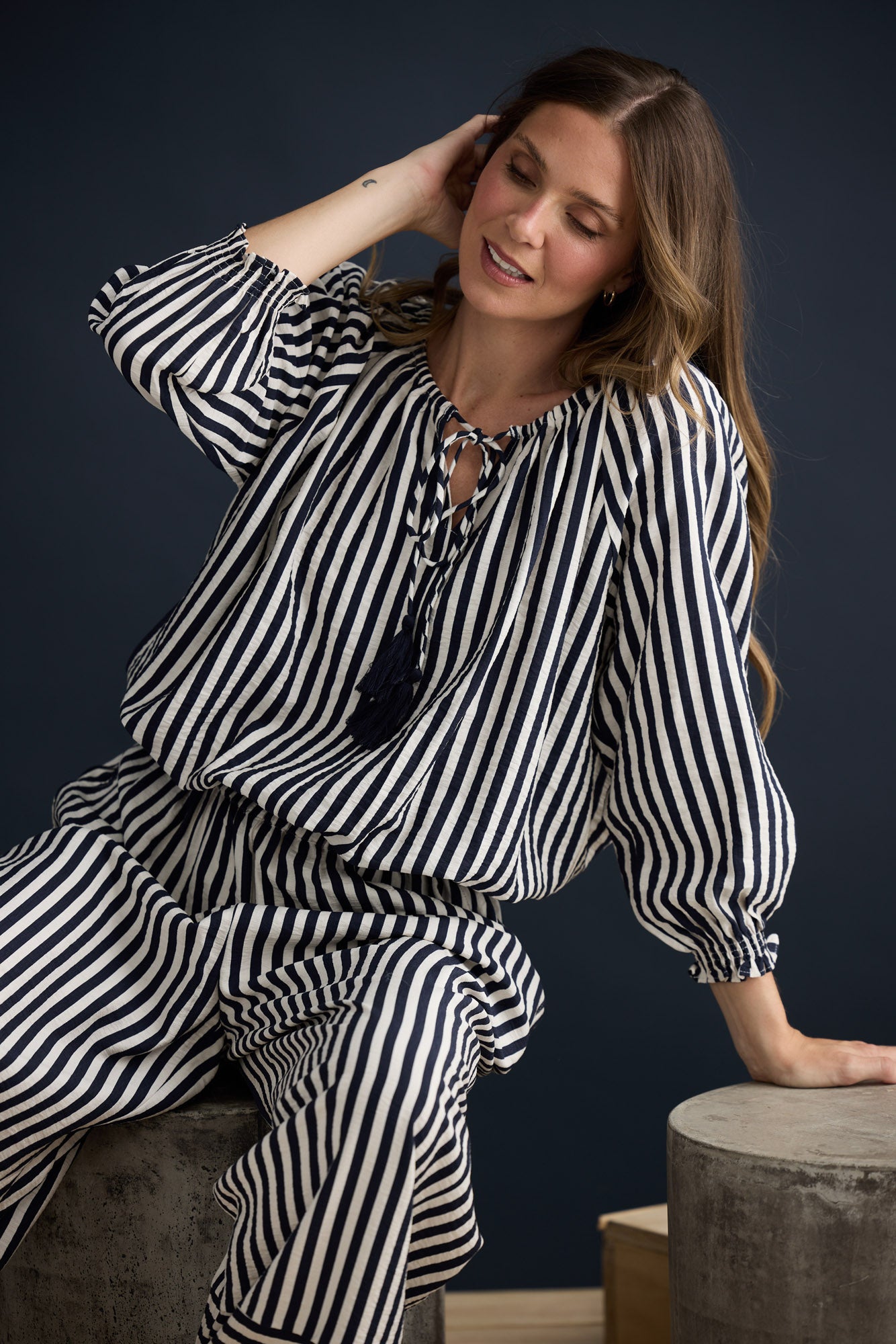 Model wearing Seaside Top Navy and White Stripe with neck ties and shirred cuffs, campaign lifestyle view