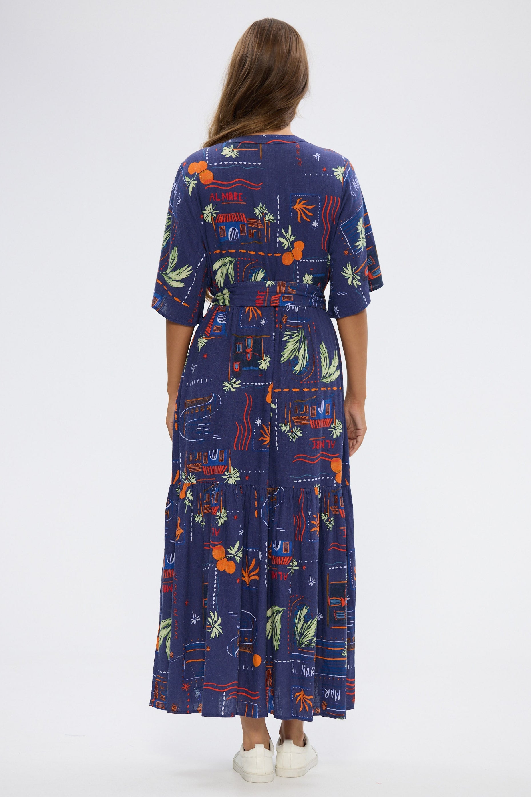 Woman wearing a long, dark blue dress with colorful geometric pattern on a white background