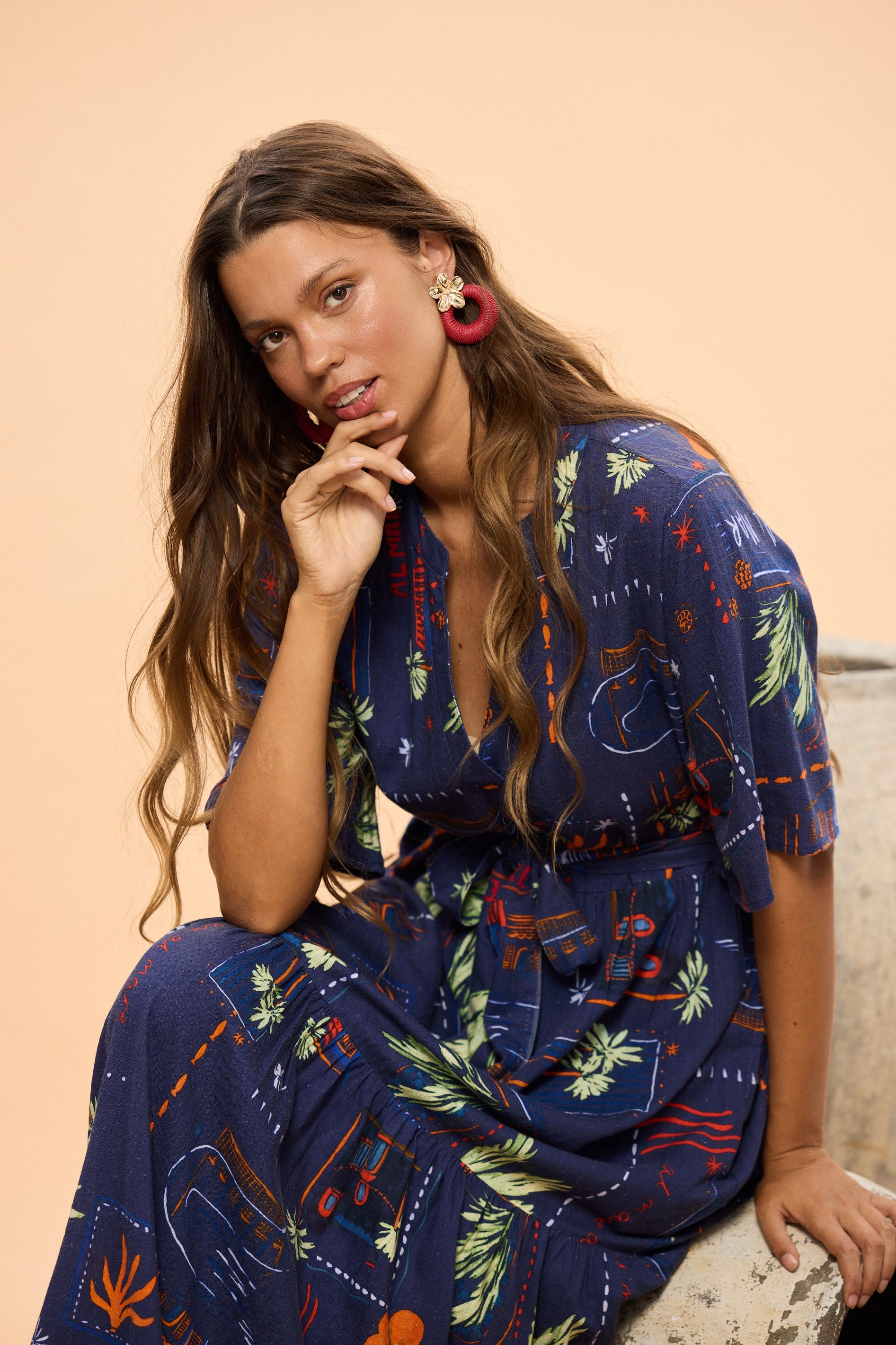 Woman wearing a blue patterned dress sitting on a beige background
