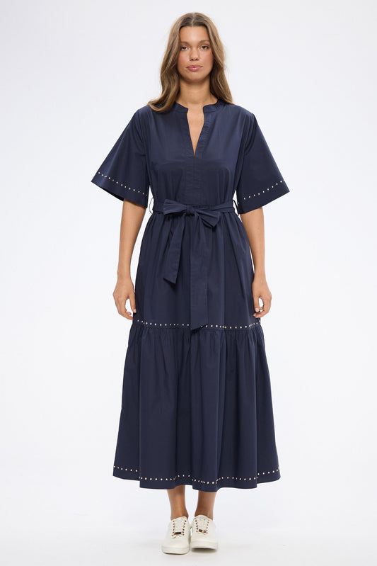 Woman wearing a navy dress with white shoes on a white background