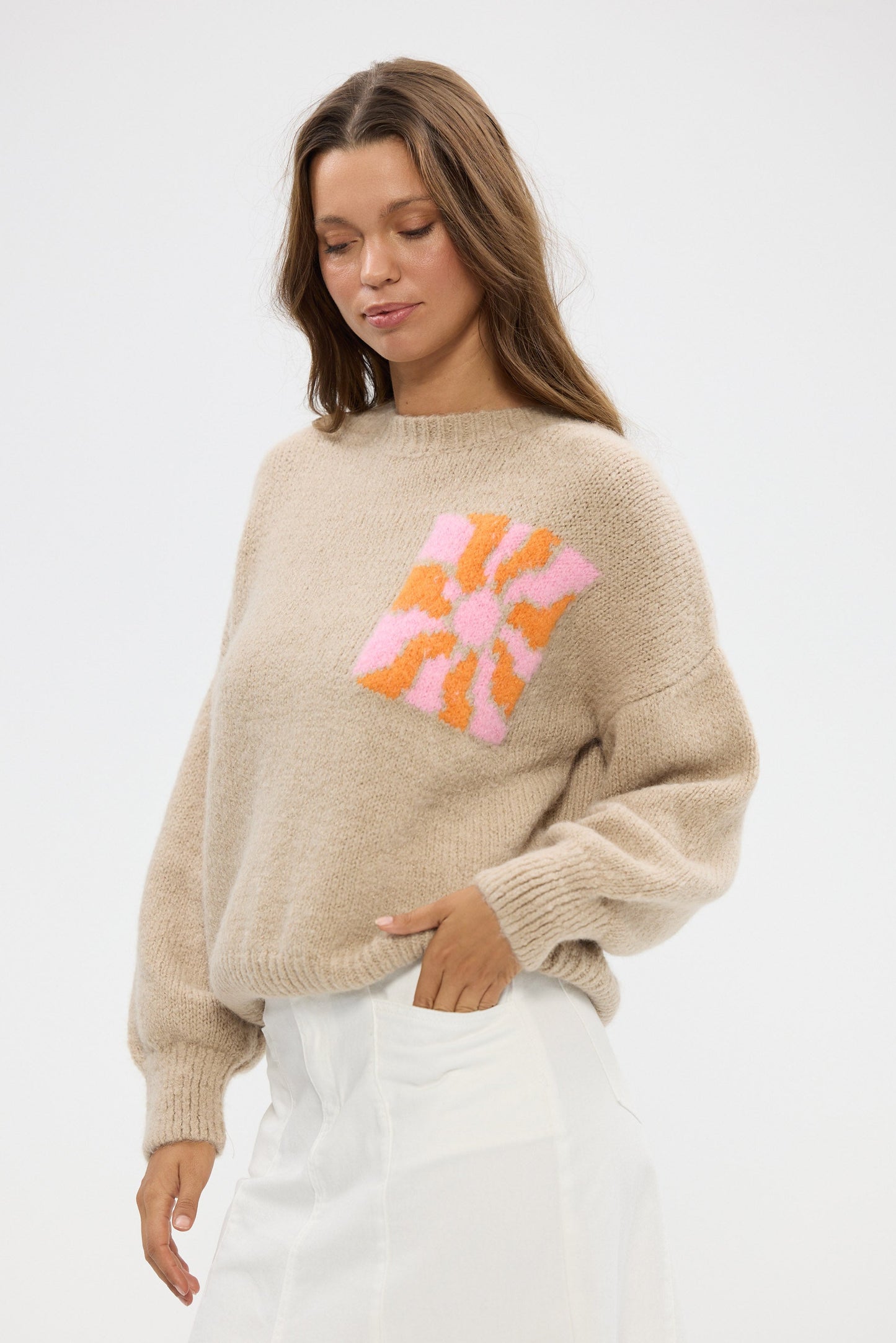 Woman wearing a beige sweater with colorful abstract design on a white background