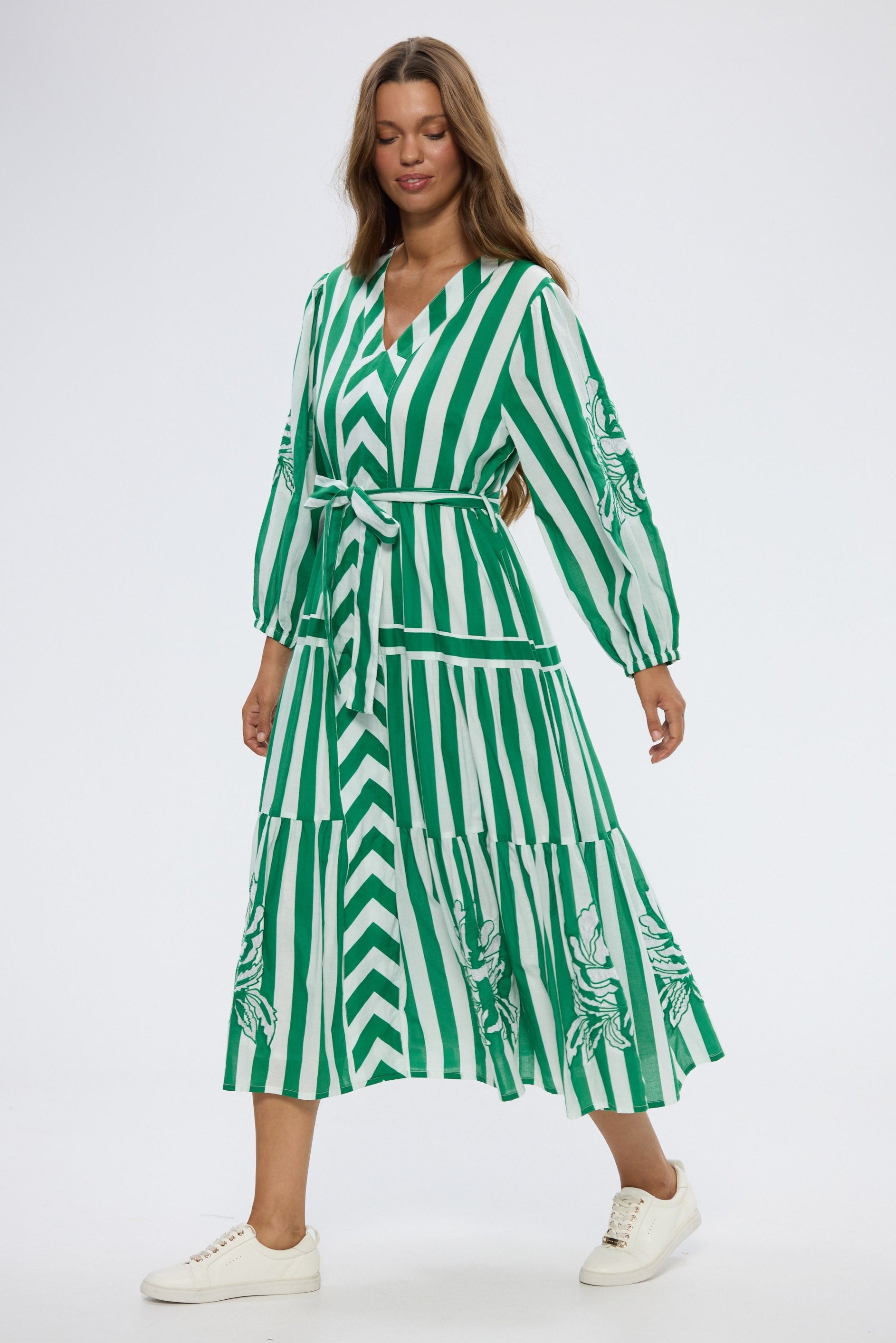 Woman wearing a green and white striped dress on a white background