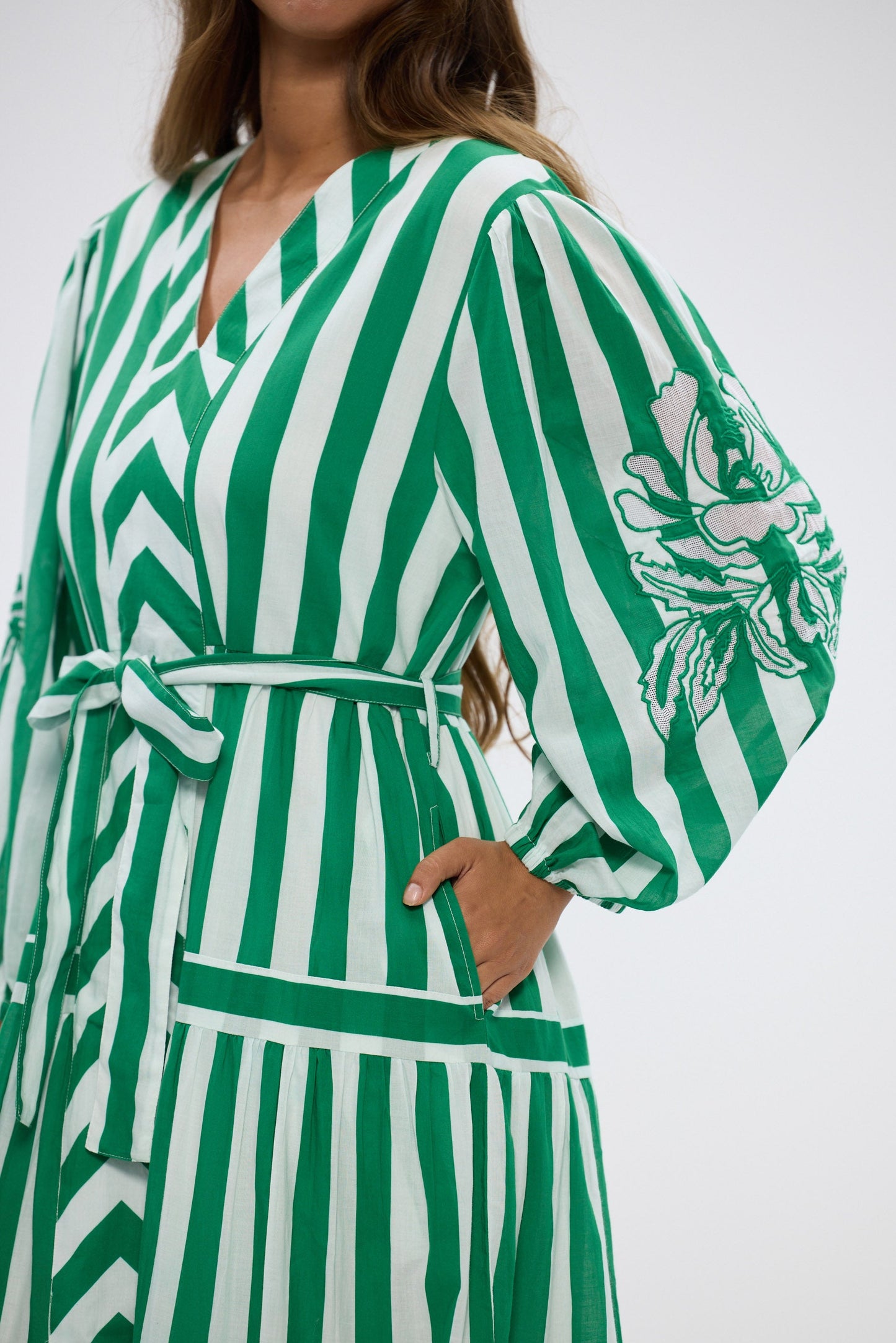 Green and white striped outfit with a belt on a plain background