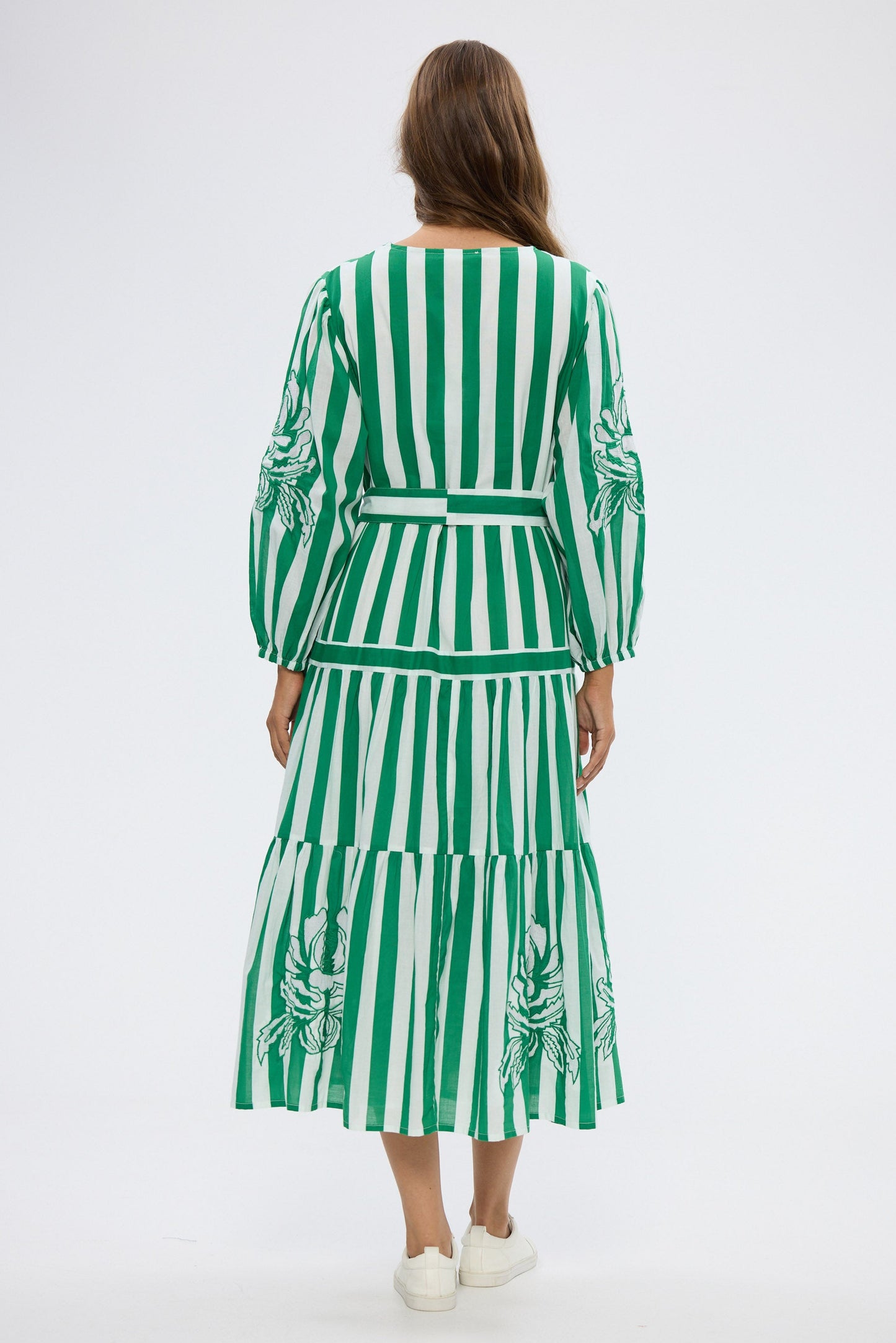 Woman wearing a green and white striped dress with a belt on a white background