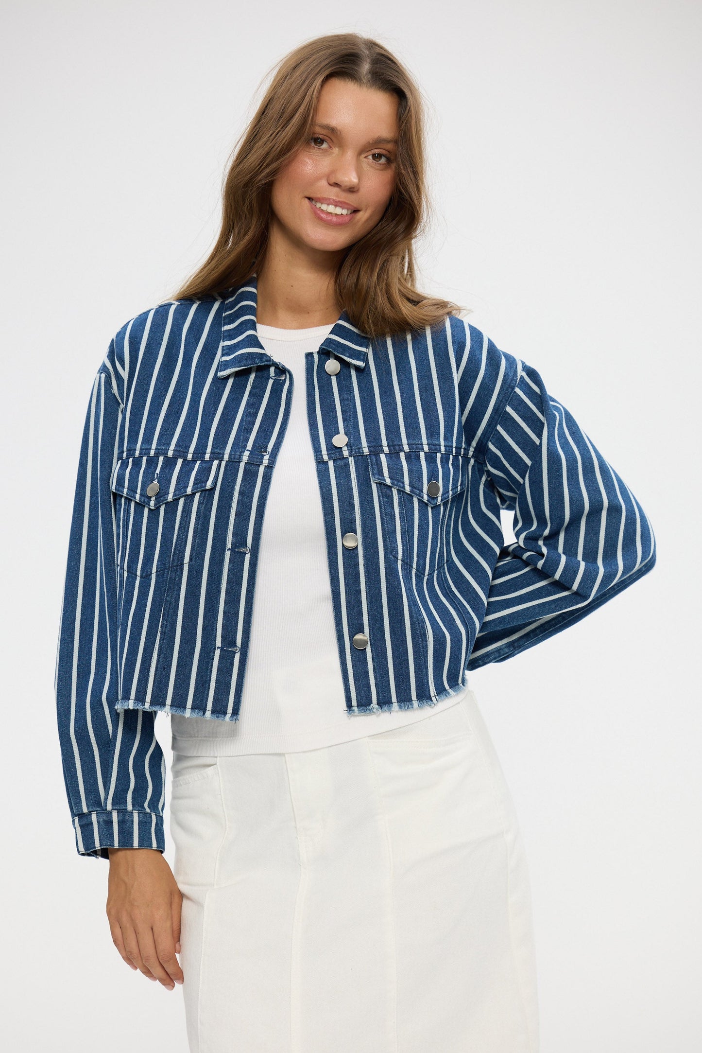 Woman wearing a blue and white striped denim jacket on a white background