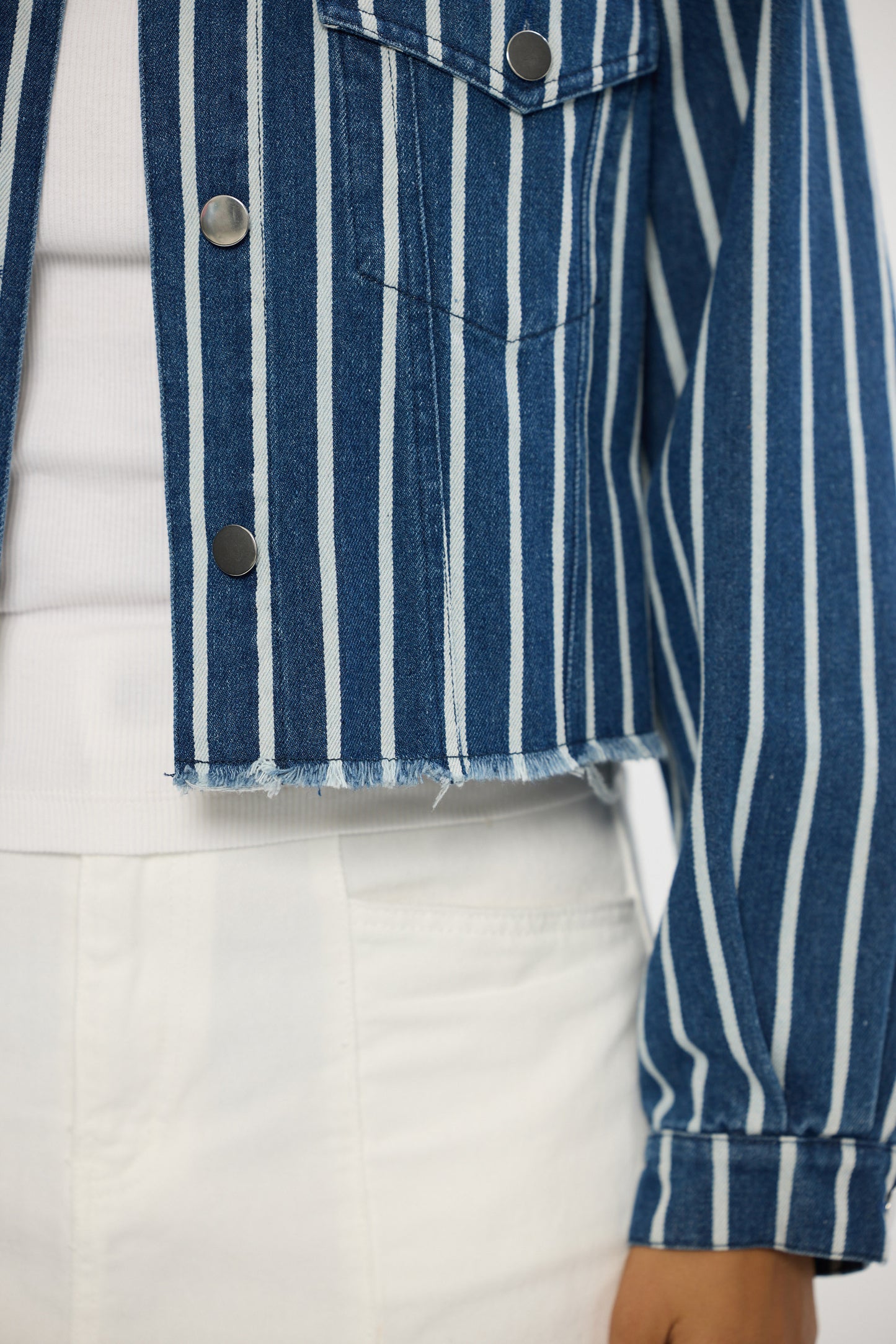 Close-up of a blue and white striped denim jacket with a white background