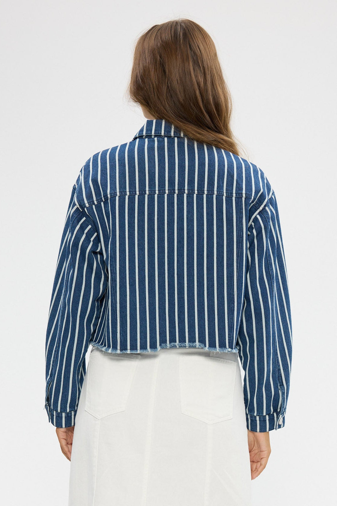 Person wearing a blue striped shirt and white pants on a white background