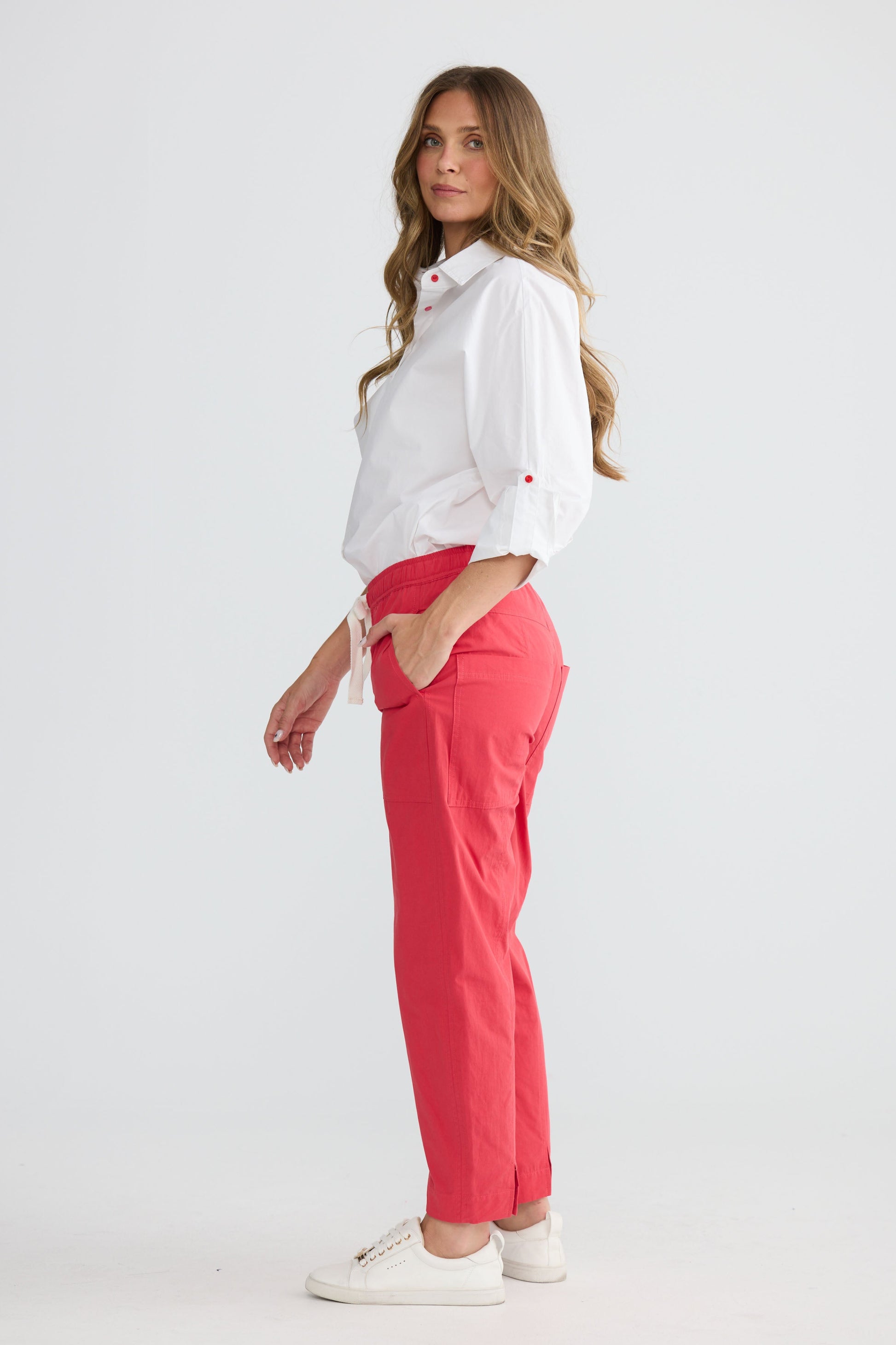 Model wearing Reva Cargo Pant Red with drawstring waist and cargo pockets, side view on white background