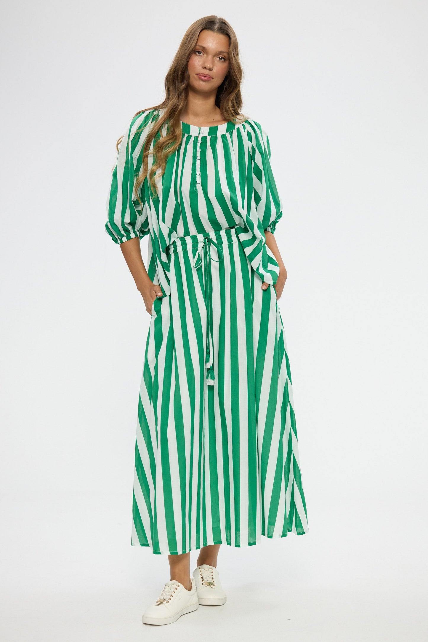 Woman wearing a green and white striped top and skirt on a white background