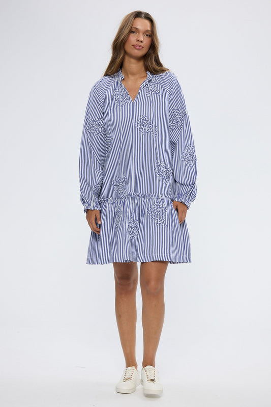 Woman wearing blue and white striped mini dress with long sleeves on white background