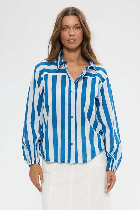 Woman wearing a blue and white striped shirt with a white skirt on a white background