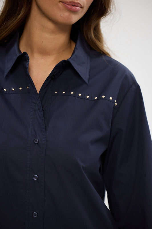 Navy blue shirt with decorative studs on a plain background