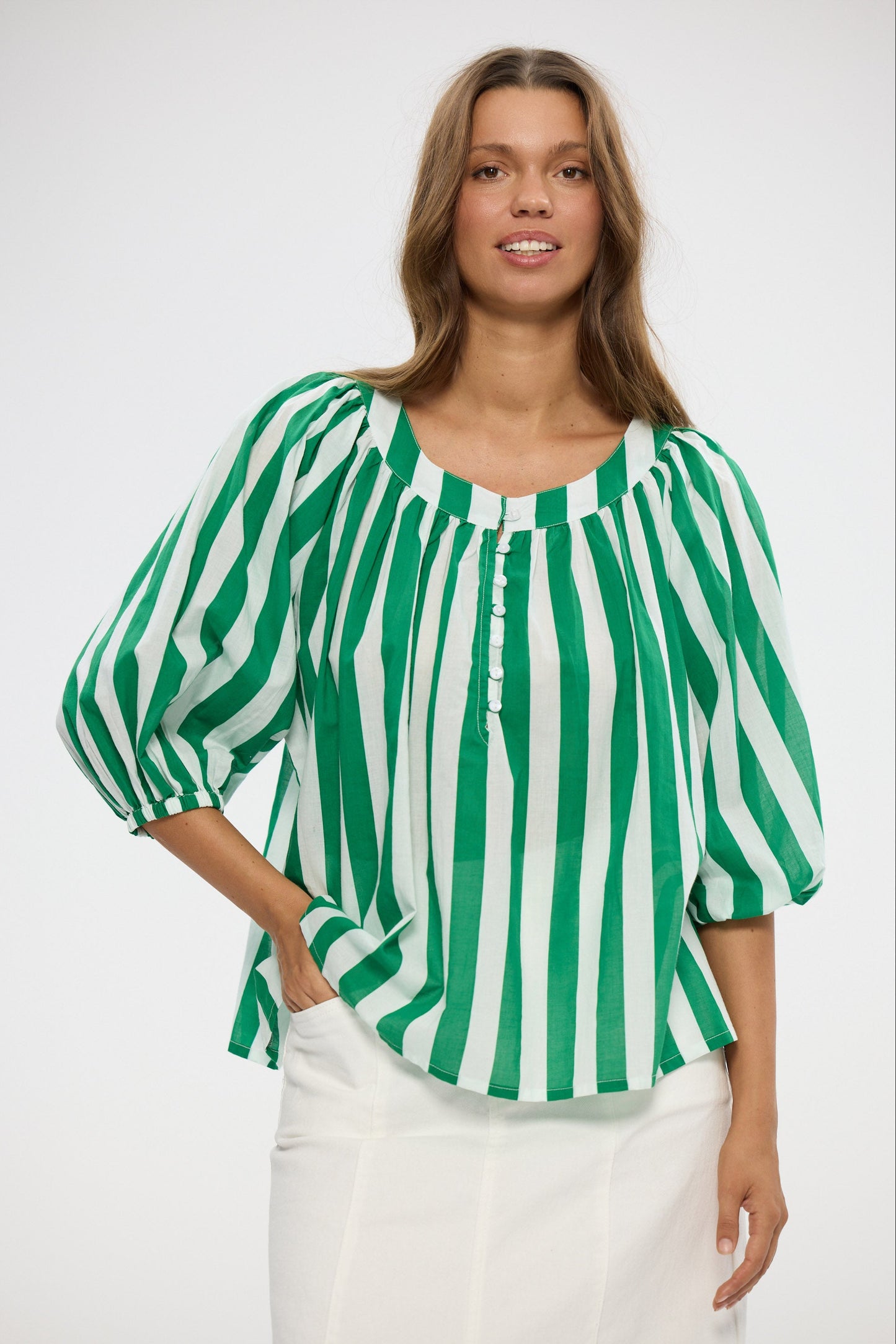 Woman wearing a green and white striped blouse against a white background