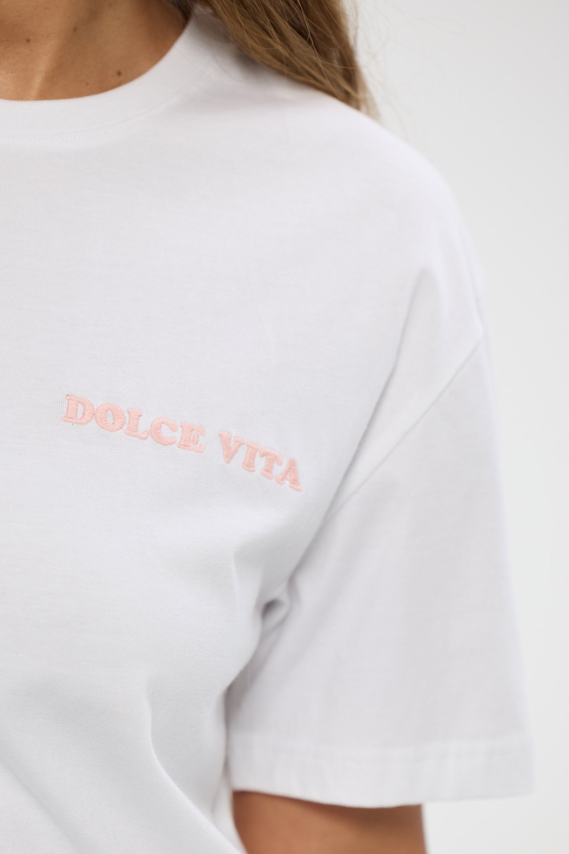 White t-shirt with 'Dolce Vita' text in pink on a plain background