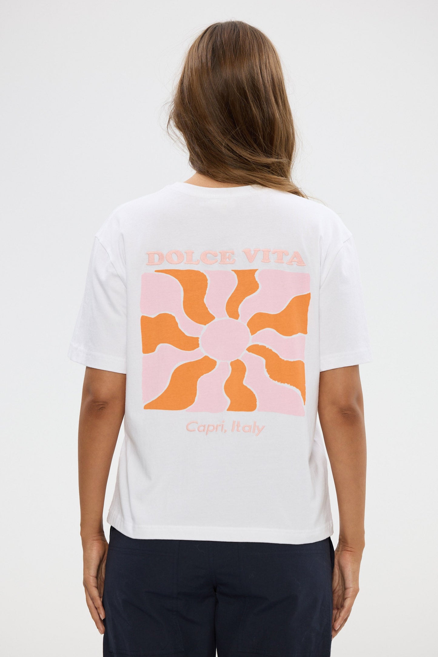 Person wearing a white t-shirt with a colorful design on the back against a white background