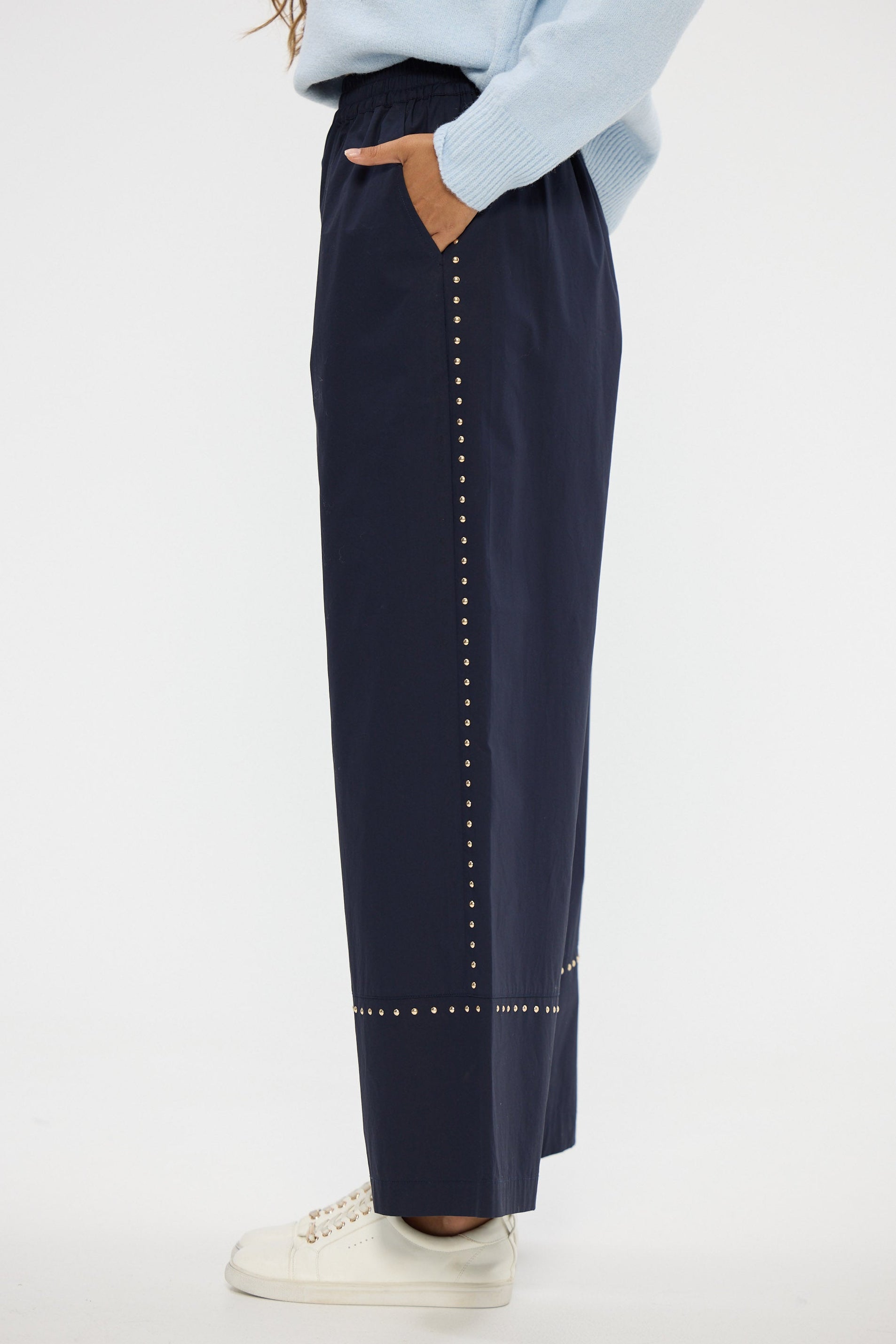 Navy pants with decorative studs on a white background