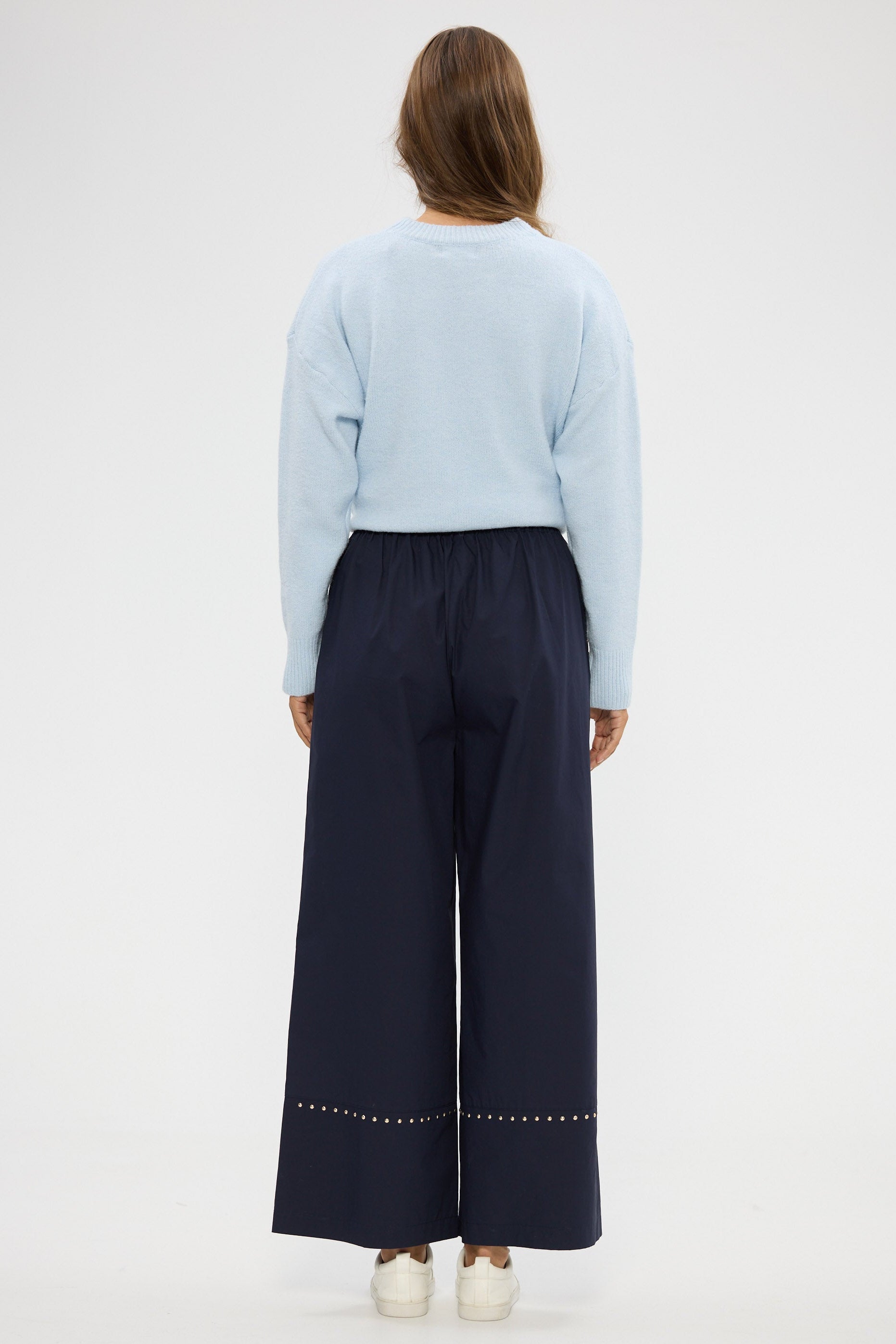 Person wearing a light blue sweater and dark blue pants on a white background