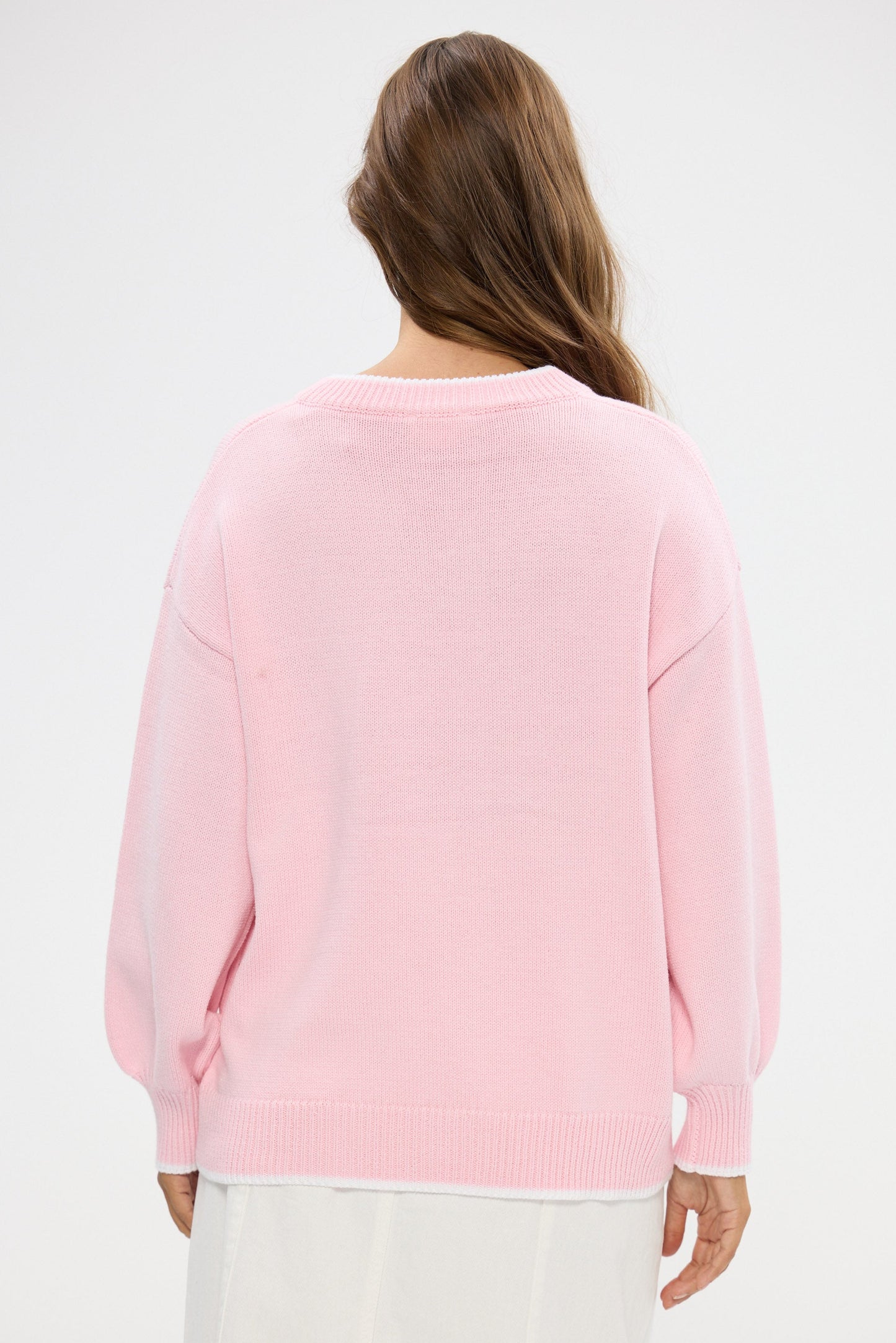 Person wearing a pink sweater on a white background