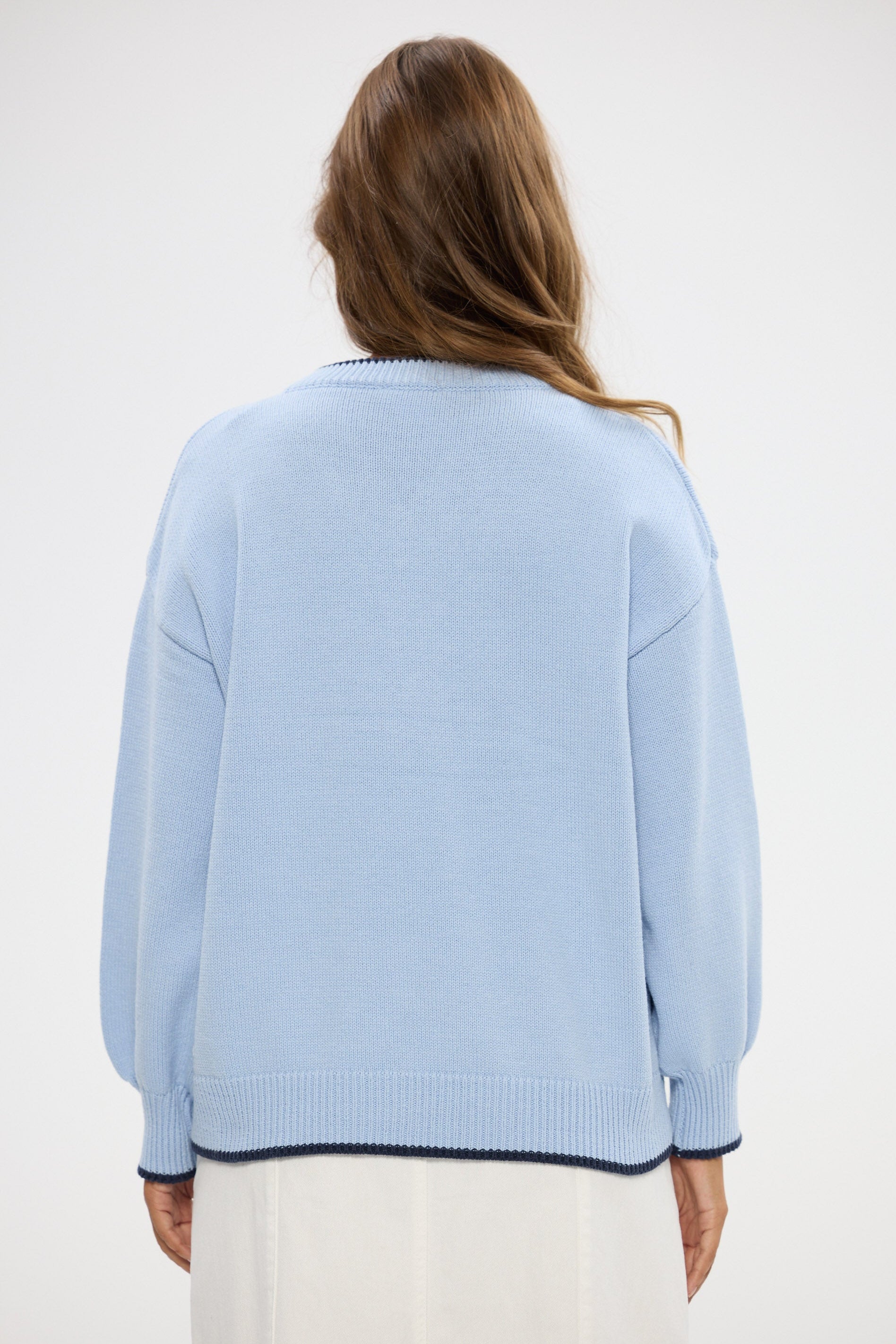 Person wearing a light blue sweater with a white background