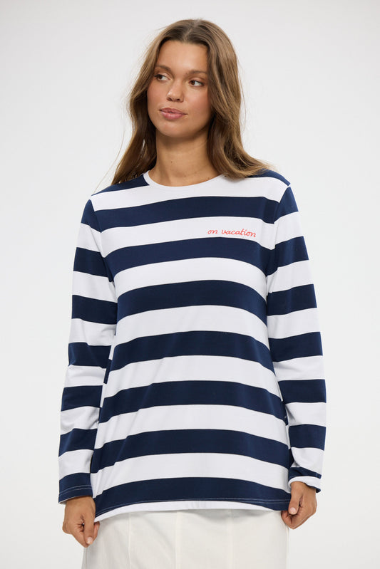 Woman wearing a navy and white striped sweater with a visible brand logo on a white background