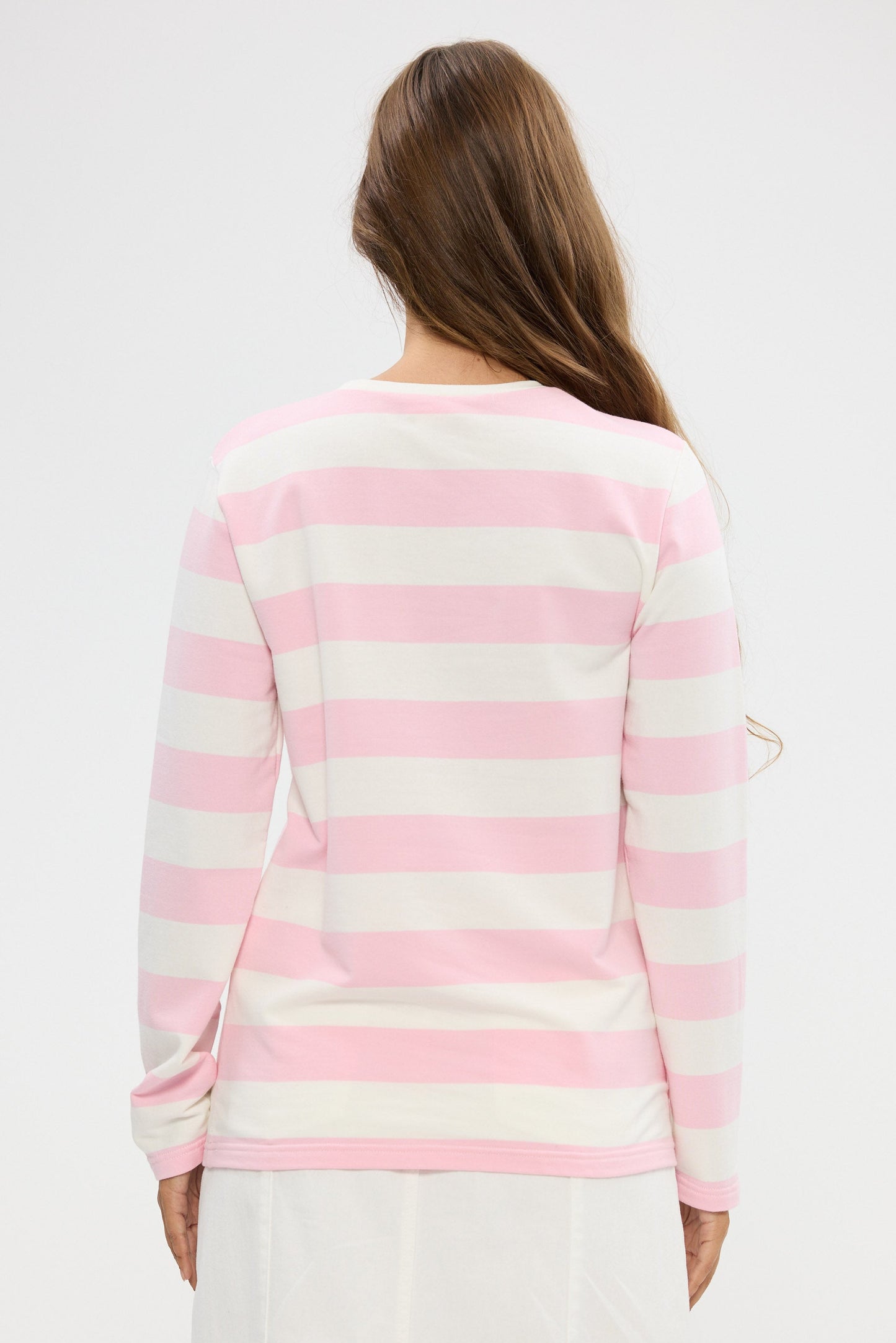 Woman wearing a pink and white striped sweater on a plain background