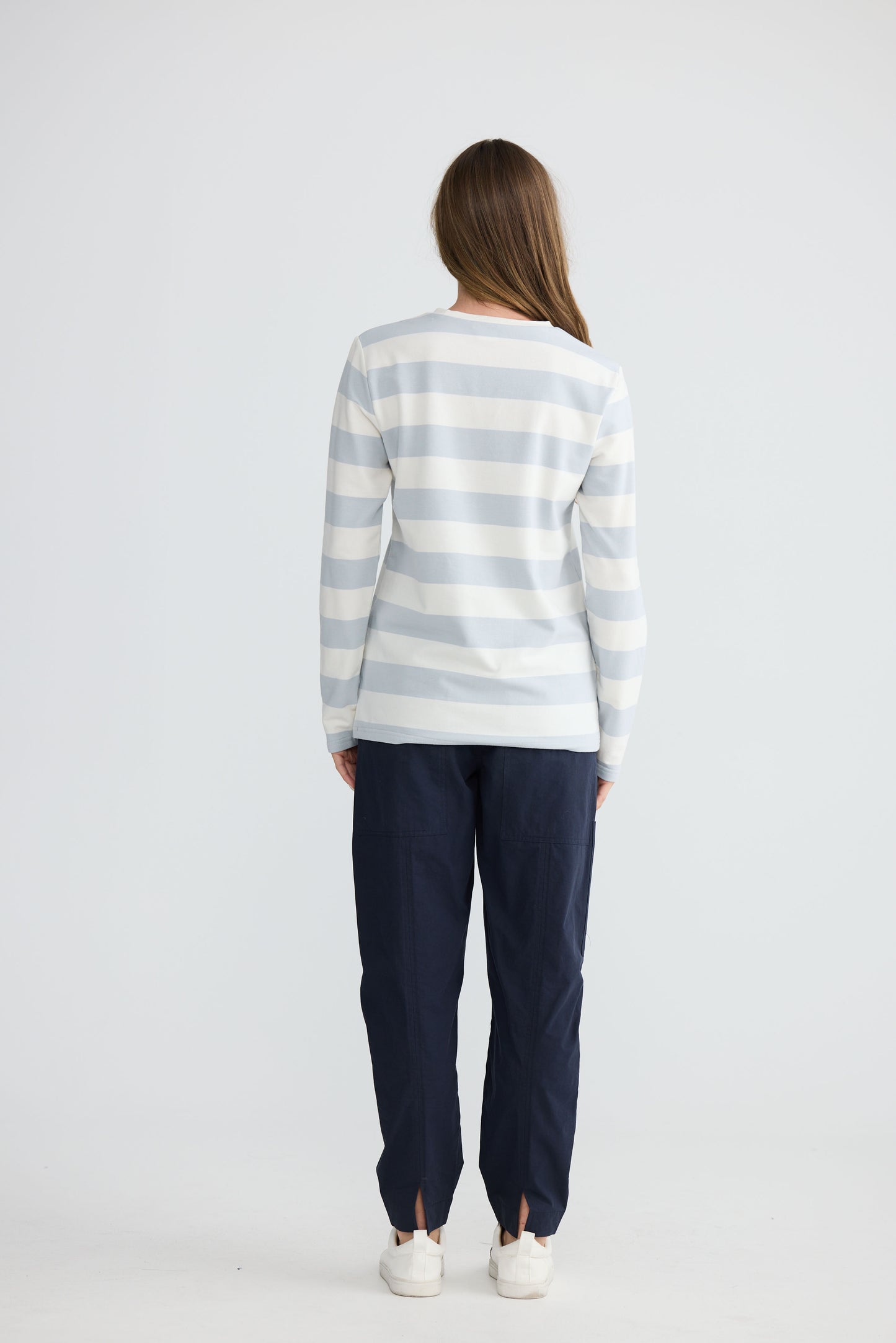 Model wearing Roam Tee Light Blue Stripe with long sleeves and striped finish, side view on white background