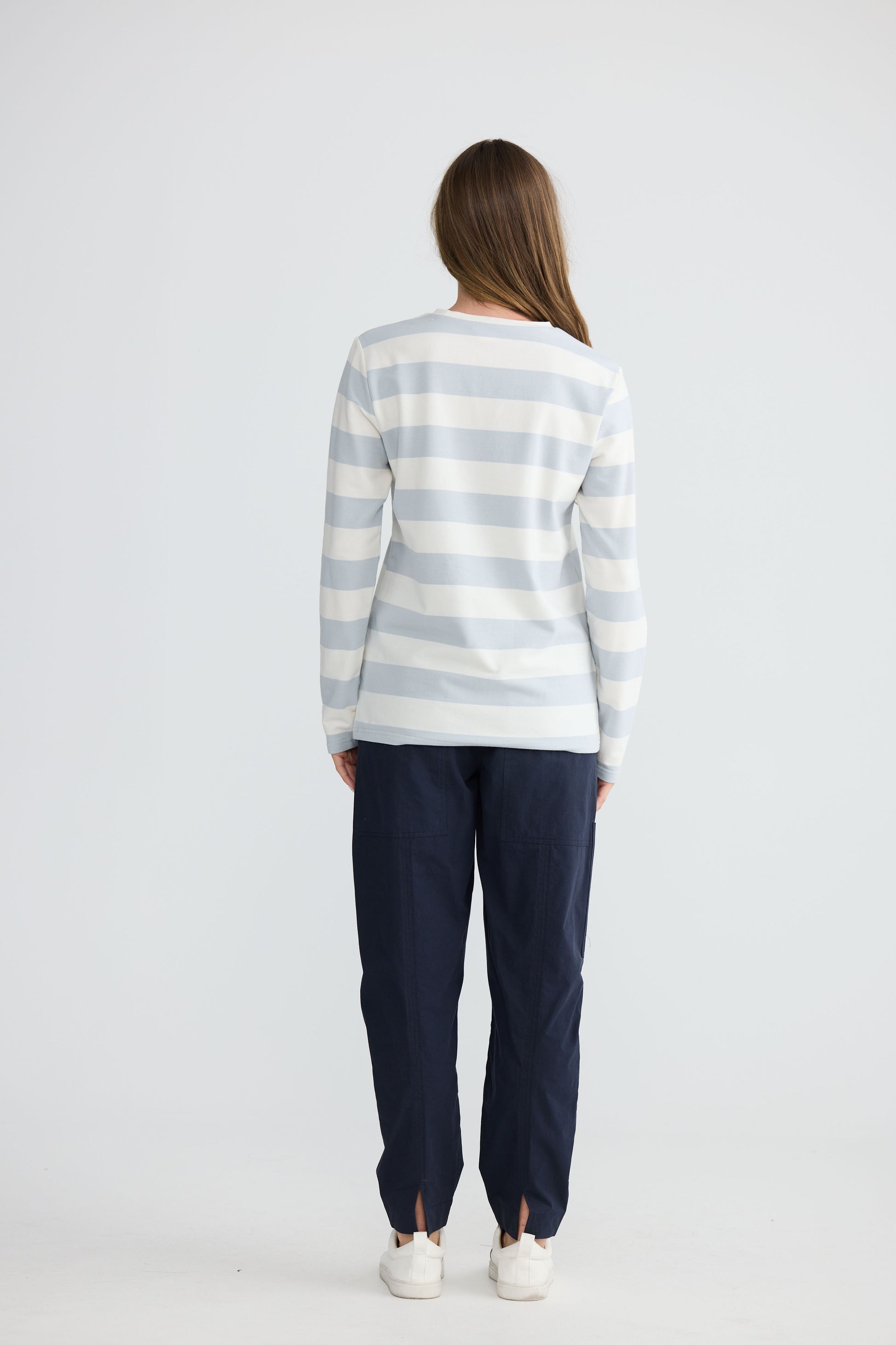 Model wearing Roam Tee Light Blue Stripe with long sleeves and striped finish, side view on white background