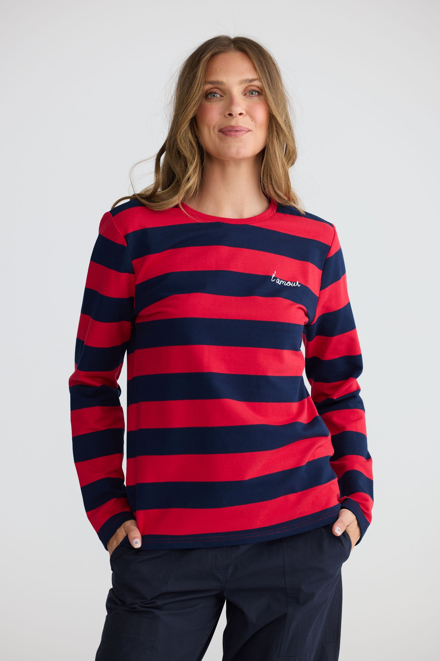 Model wearing Roam Tee Red and Navy Stripe with long sleeves and striped finish, side view on white background