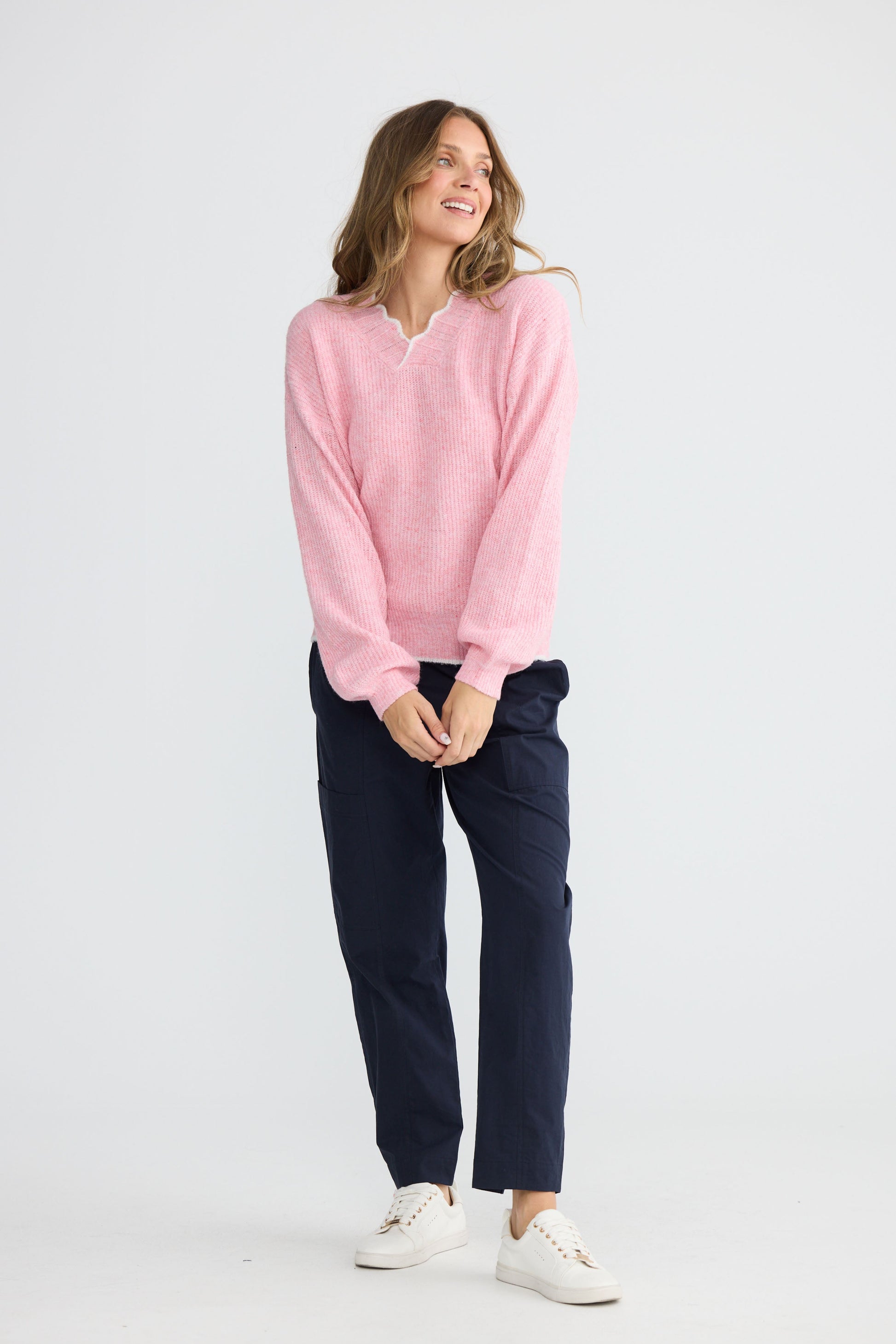 Model wearing Ocean Knit Pink with scalloped V-neckline, detail view on white background