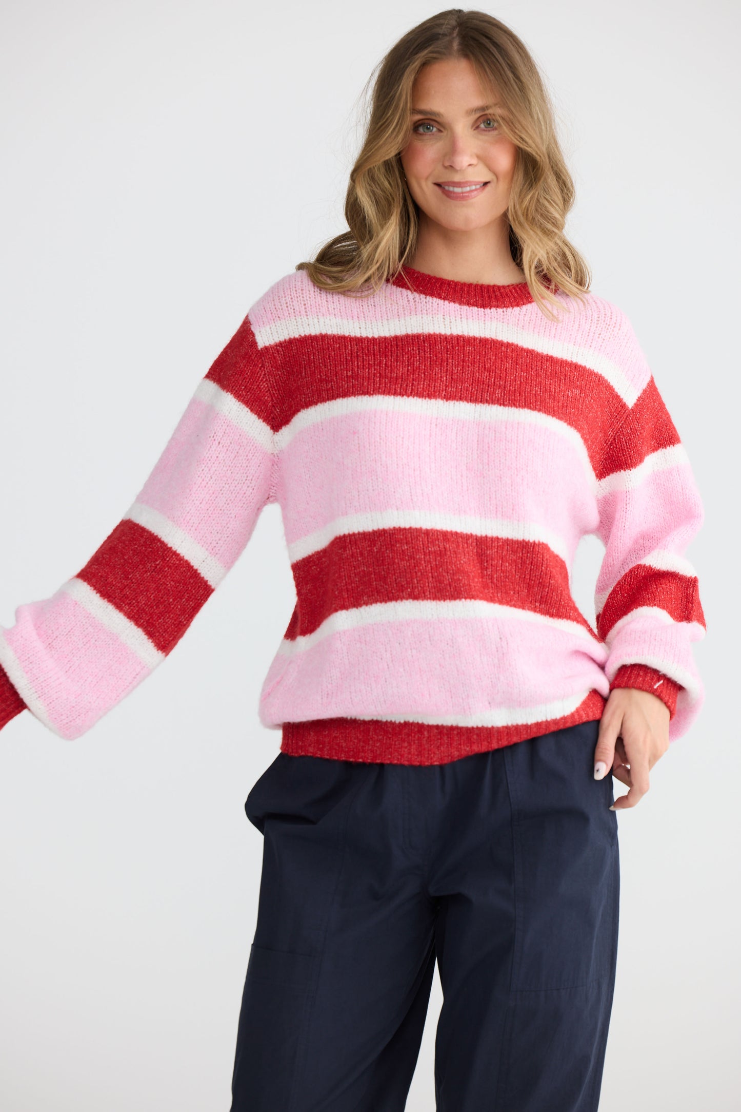 Model wearing Cove Knit Pink Multi Stripe with multi stripe knit finish, side view on white background