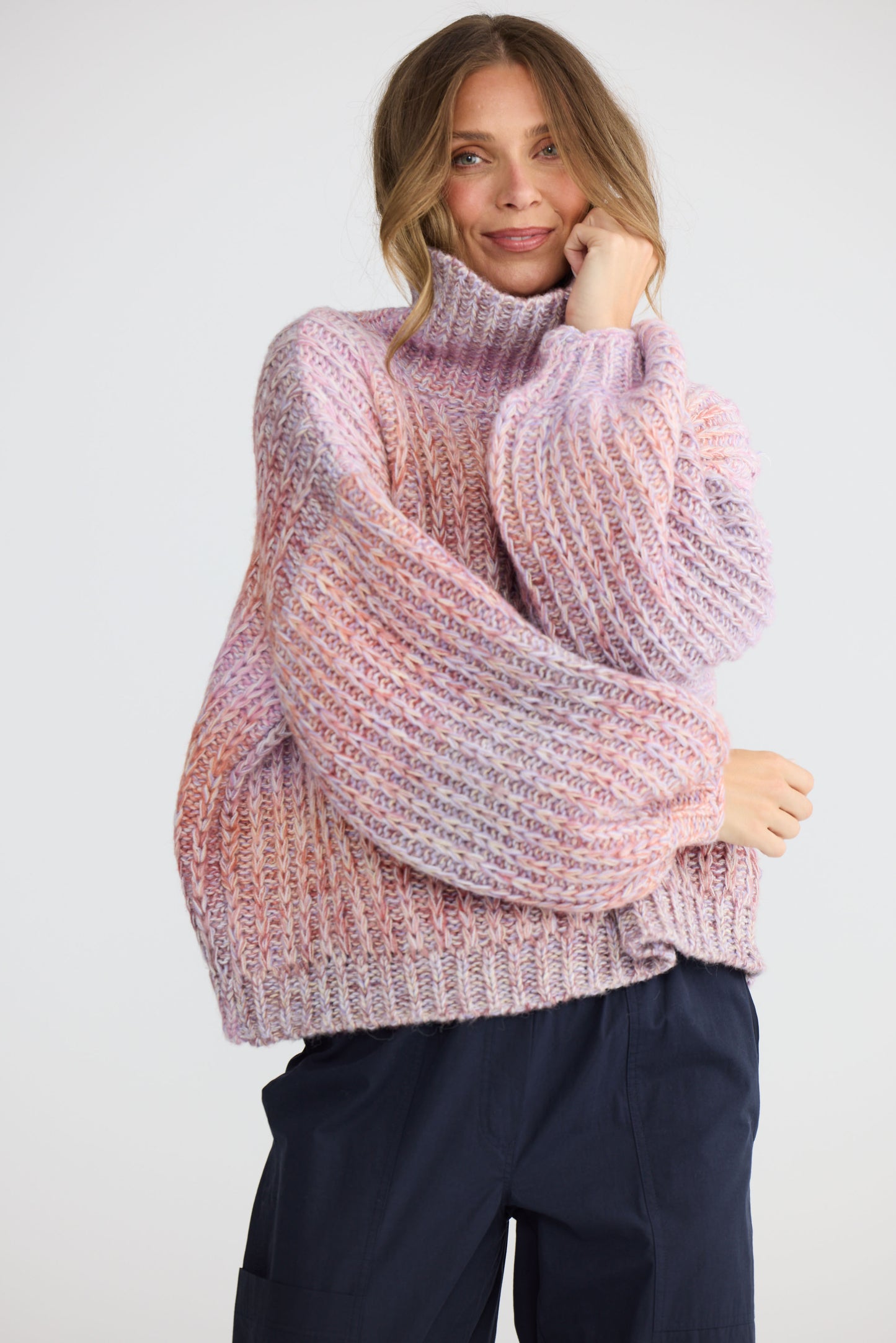 Model wearing Olas Knit Pink Ombre with chunky high neckline, side view on white background