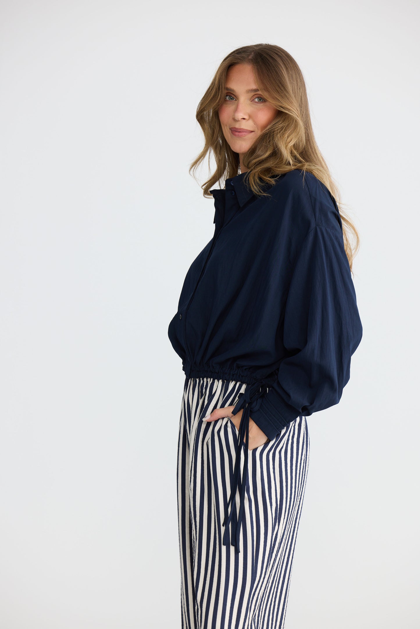 Model wearing Ripple Shirt Navy with relaxed shirt silhouette, side view on white background