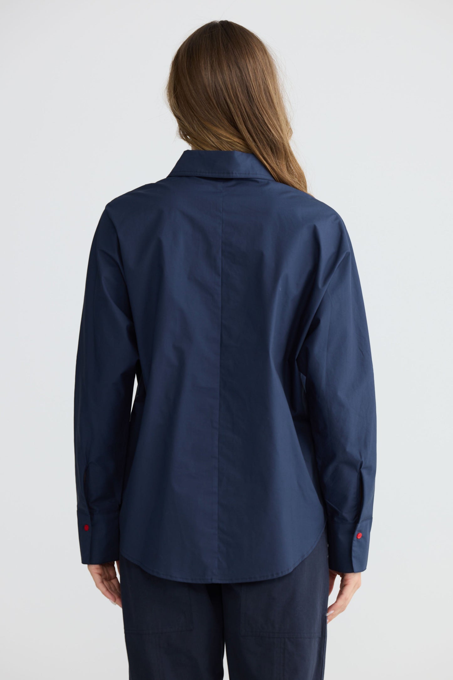 Model wearing Fae Shirt Navy with contrast buttons and stitching, side view on white background