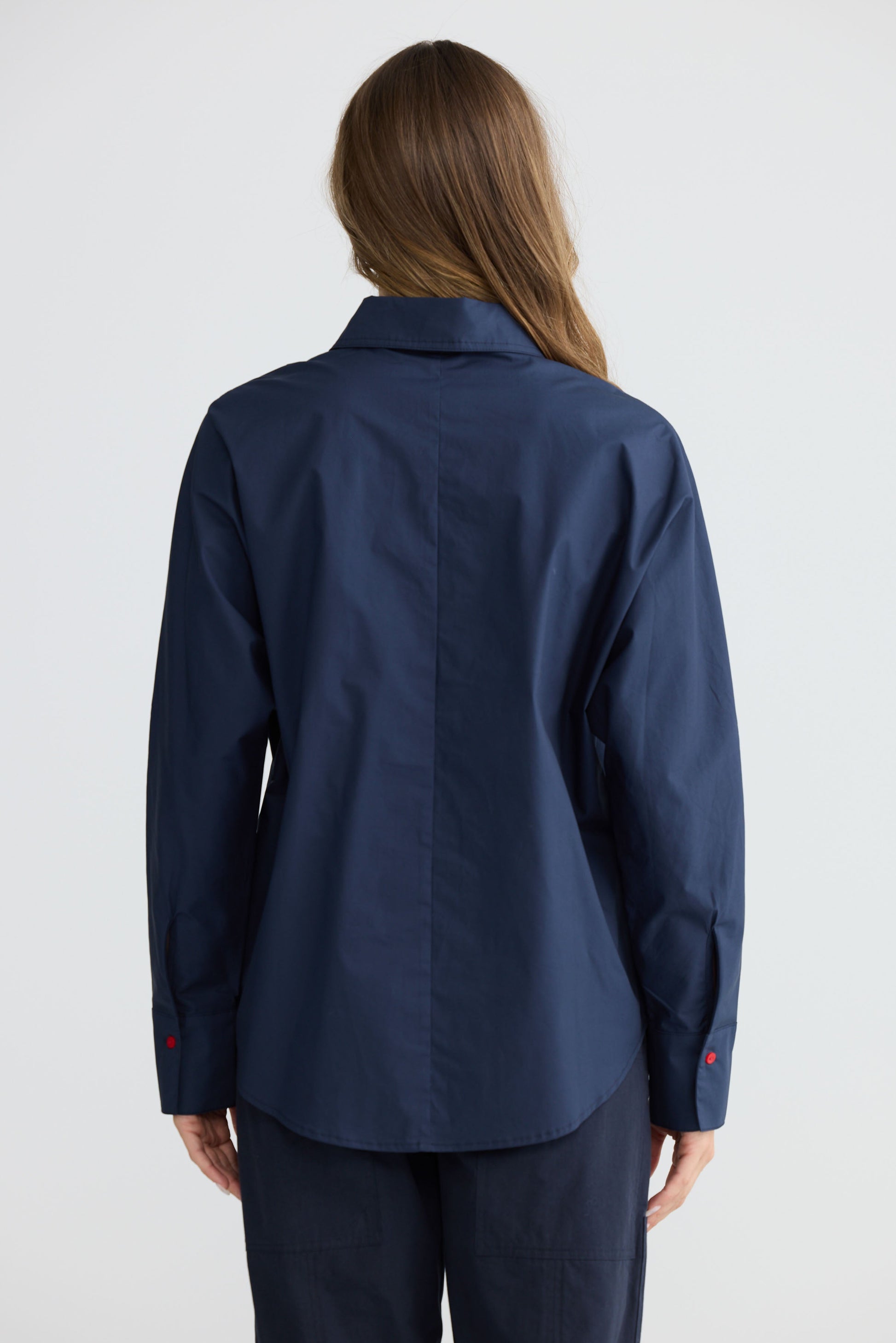 Model wearing Fae Shirt Navy with contrast buttons and stitching, side view on white background