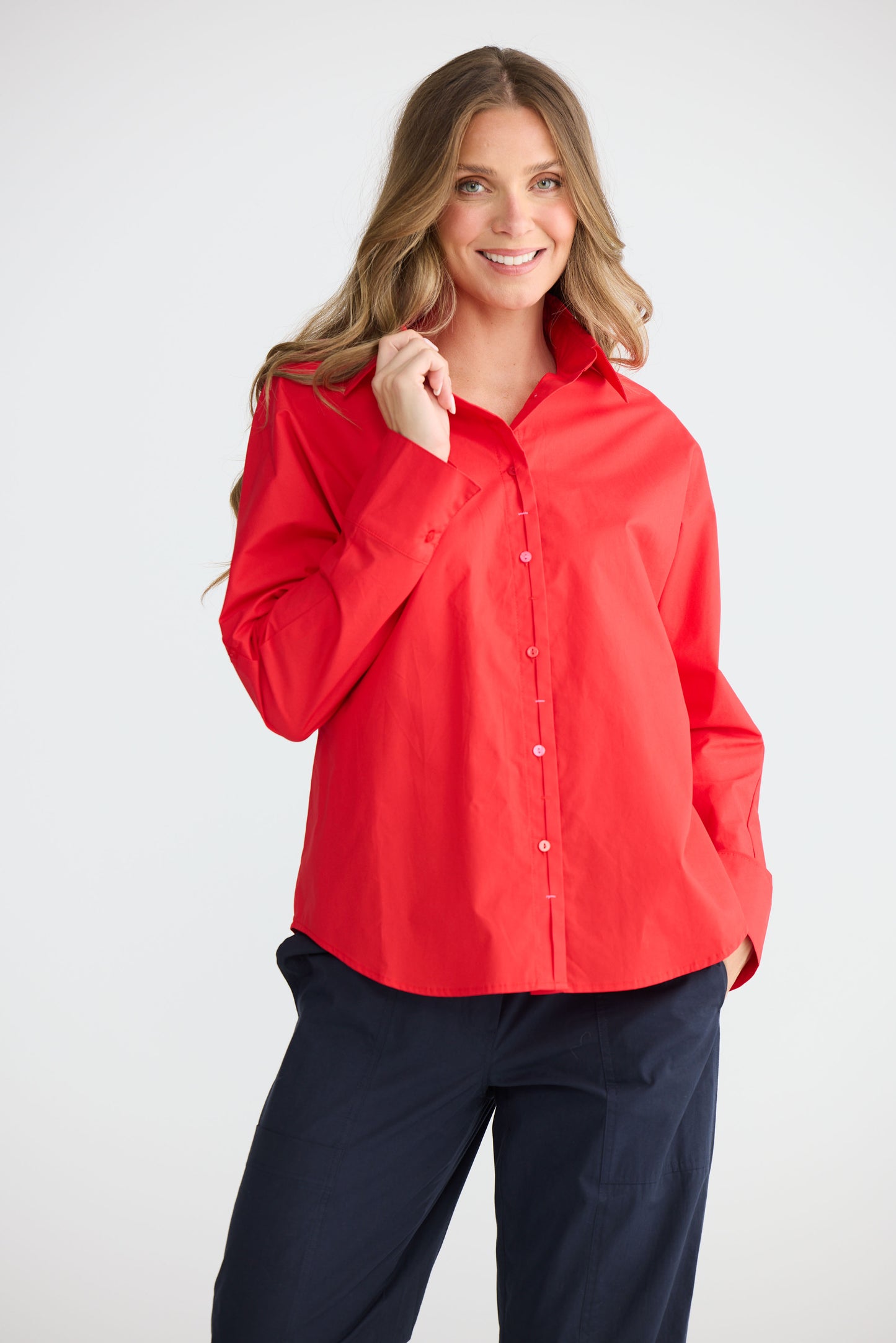 Model wearing Fae Shirt Red with contrast buttons and stitching, detail view on white background