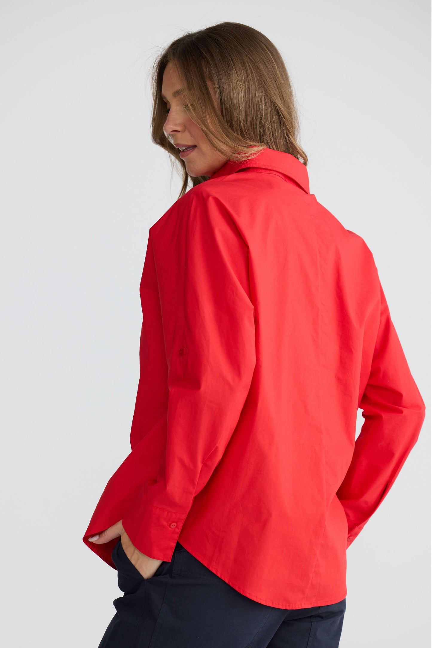 Model wearing Fae Shirt Red with contrast buttons and stitching, back view on white background