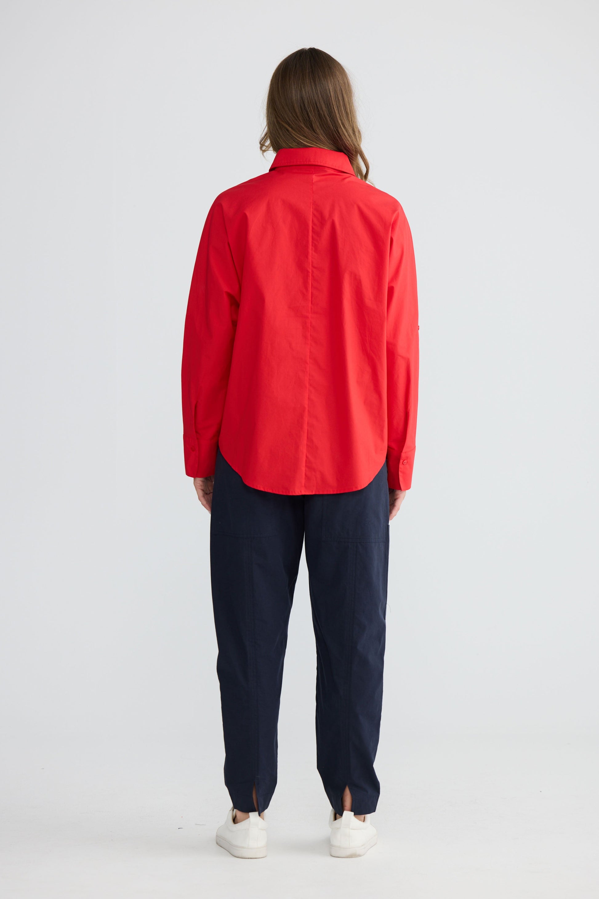Model wearing Fae Shirt Red with contrast buttons and stitching, side view on white background